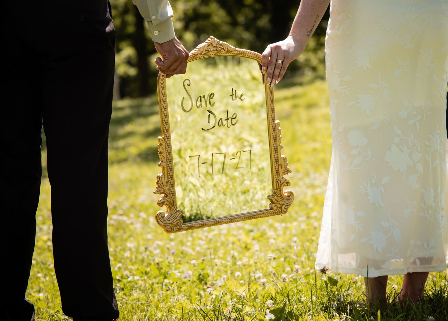 Couple holding ornate gold framed Save the Date sign in sunny garden for wedding date 7-17-17.