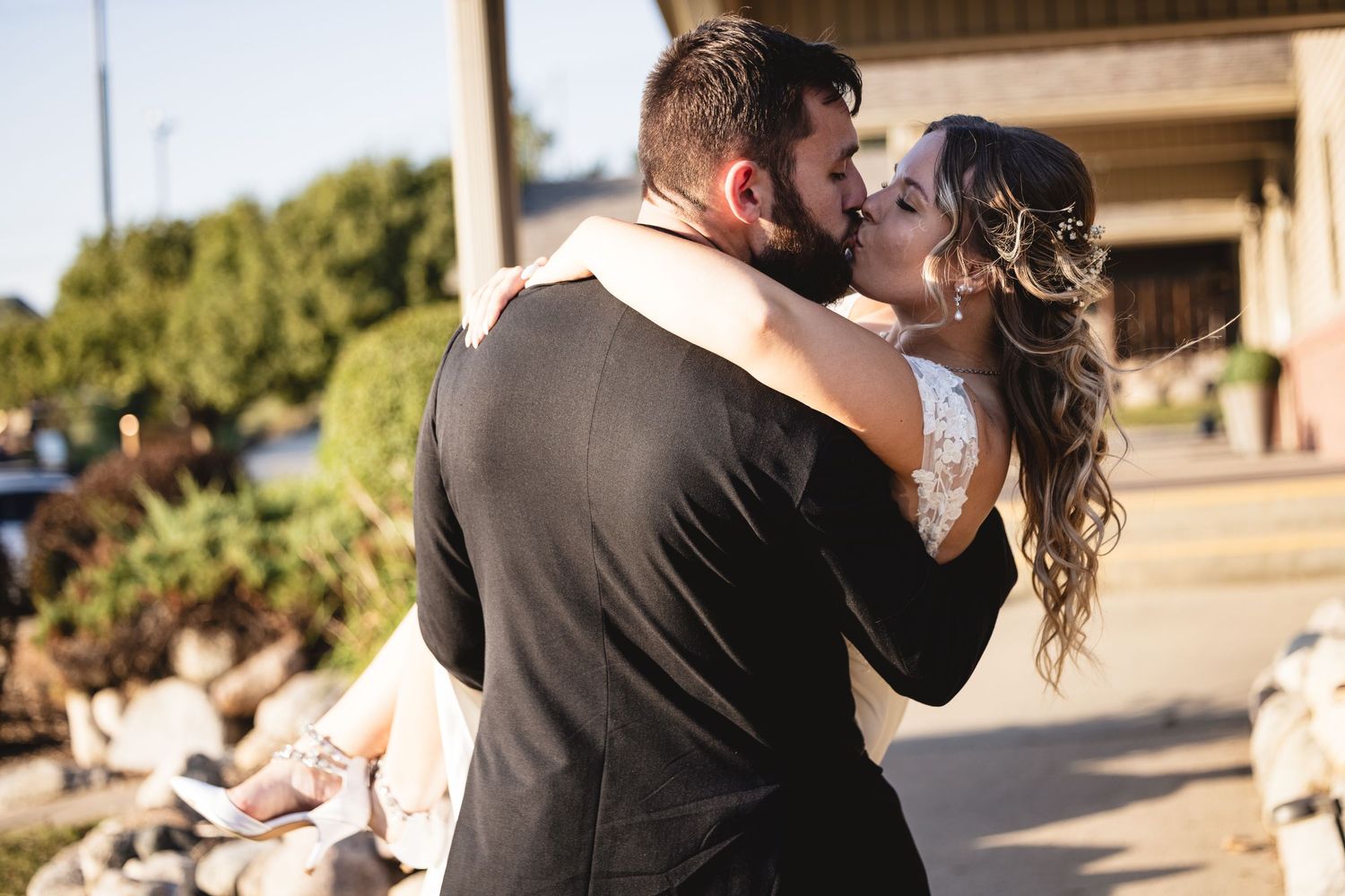 Bride and groom share a romantic kiss outside during their wedding day portraits.