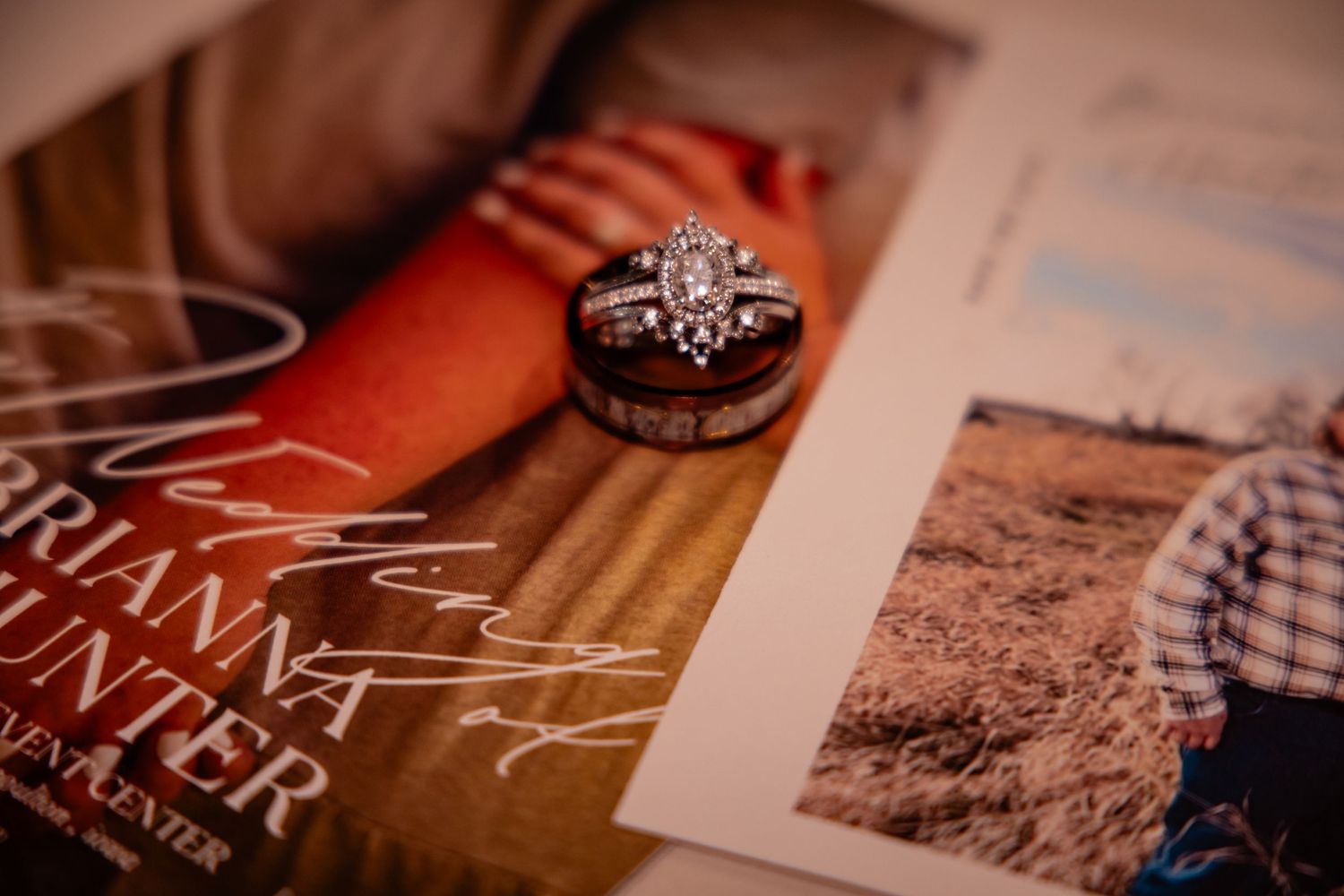 Oval halo diamond engagement ring and wedding bands displayed on wedding invitation suite.