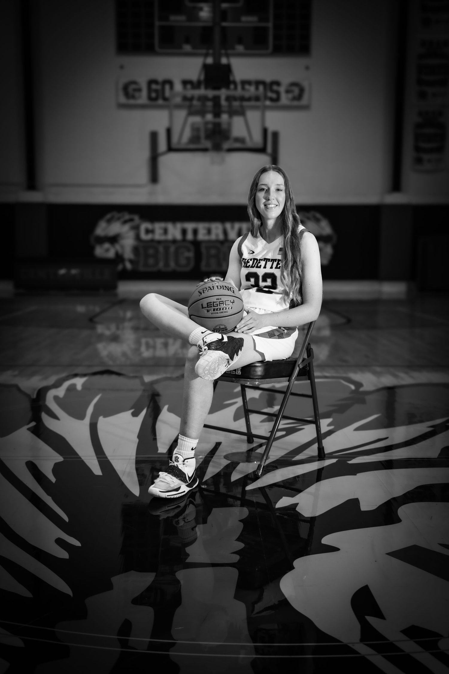 Female basketball player #22 poses with ball on gym floor in black and white photo at Centerville school.