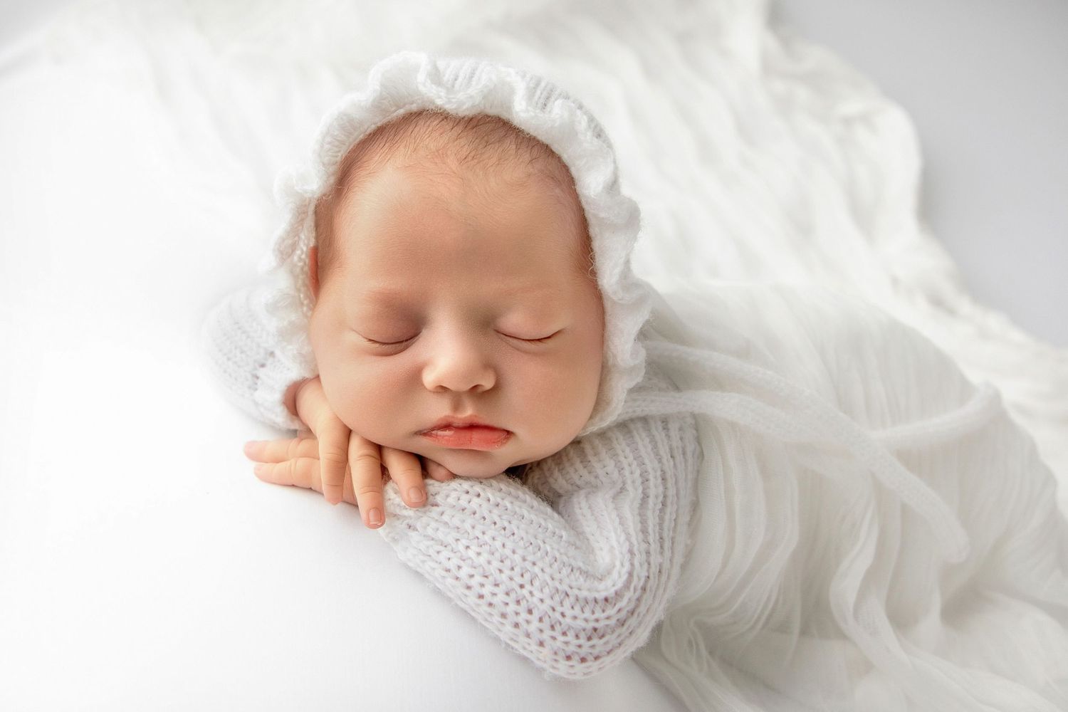 Close up newborn photos showing baby face and tiny hands in soft knit wrap