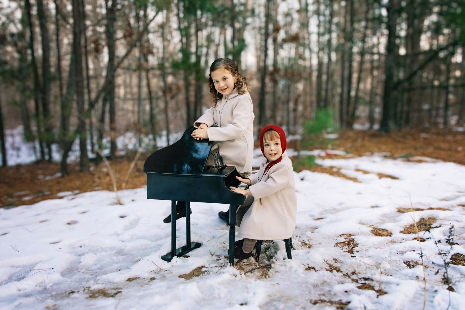 Winter forest photoshoot featuring cream colored outfits in snowy woodland setting.