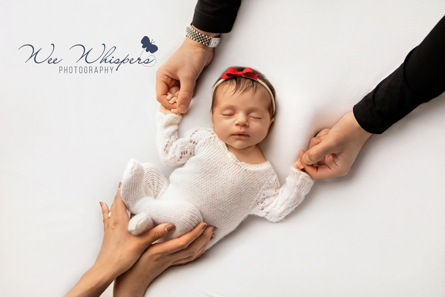 Parents sitting on a bed, looking lovingly at their swaddled newborn during newborn photoshoot in Central New Jersey