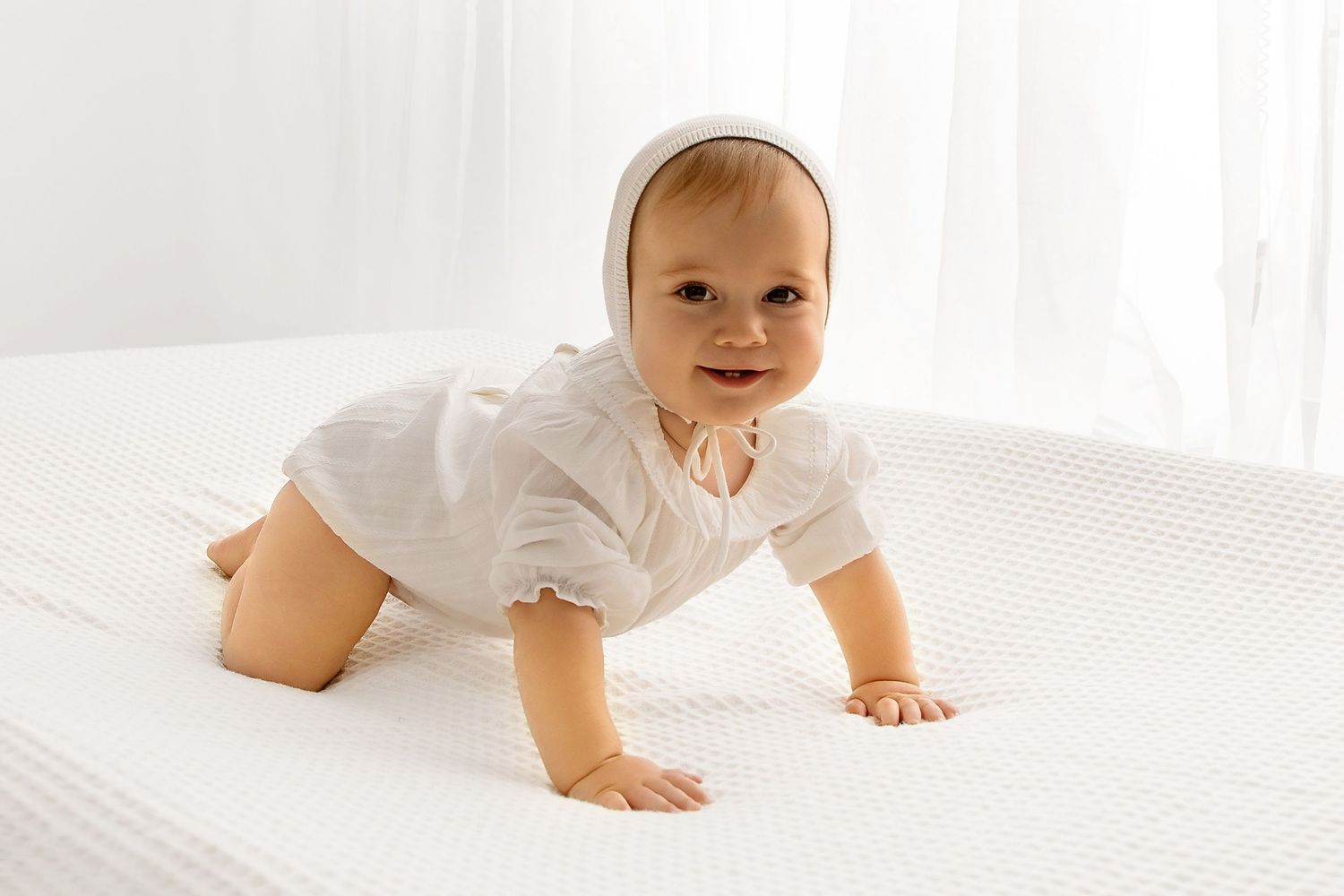 Smiling baby crawling on soft blanket styled for first birthday photoshoot session