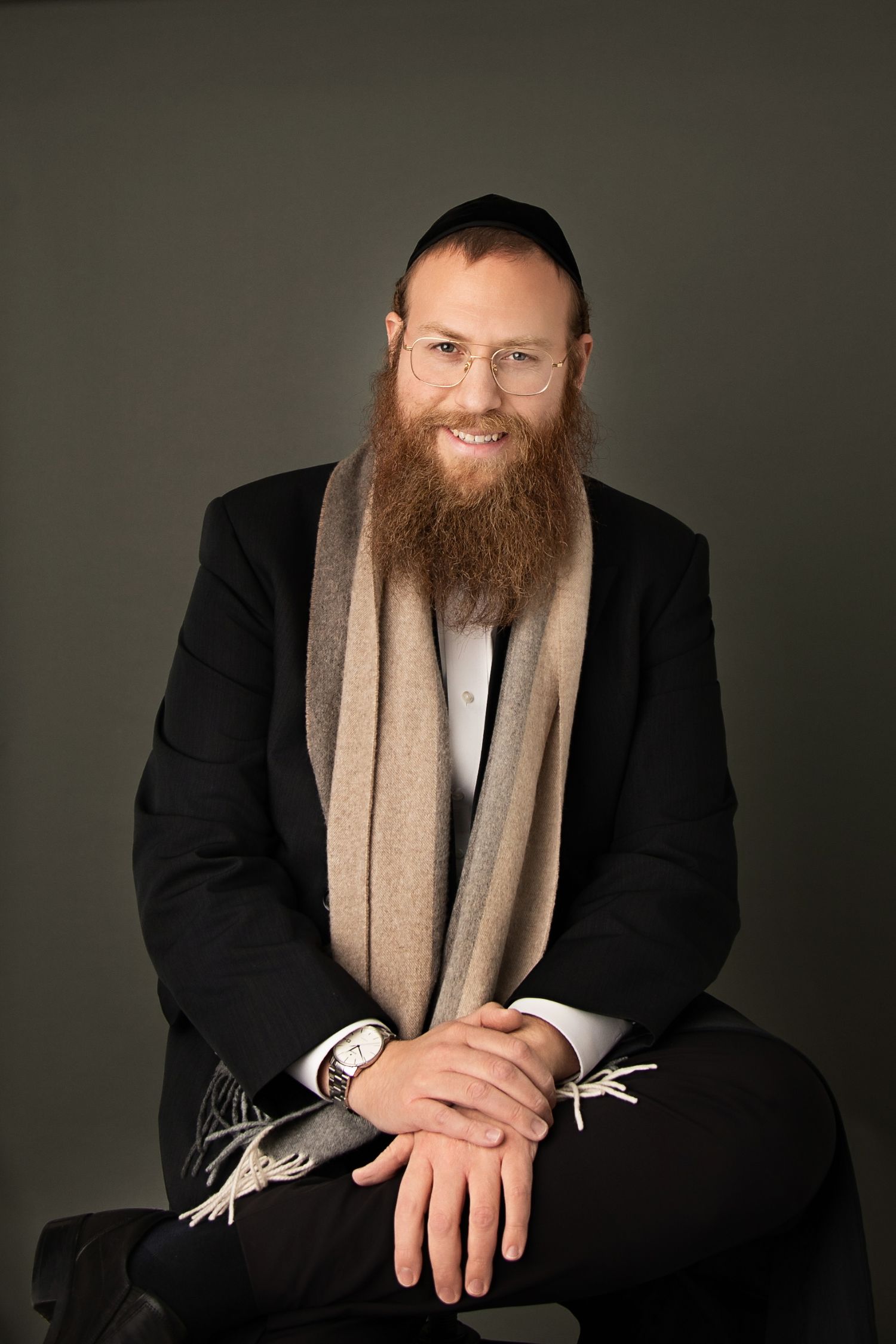 Formal studio portraits featuring black suit and tan scarf against dark backdrop.