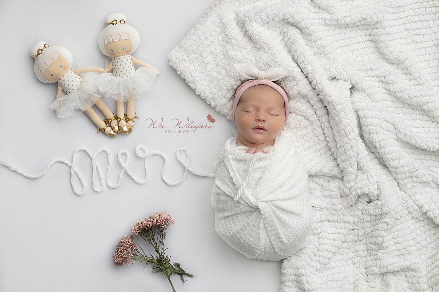 Sleeping newborn wrapped in blush pink fabric