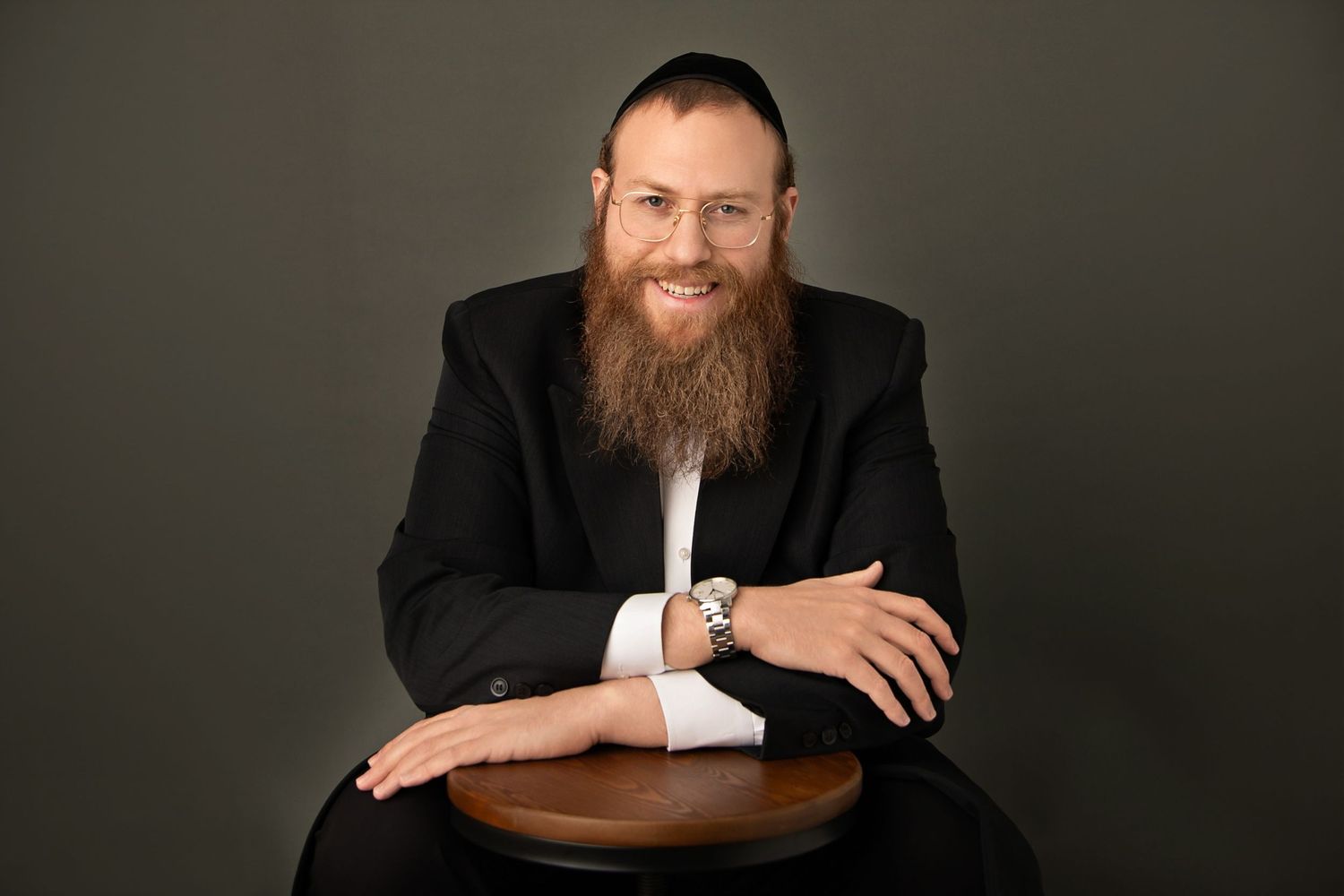 Professional portrait series in black suit against dark studio background.