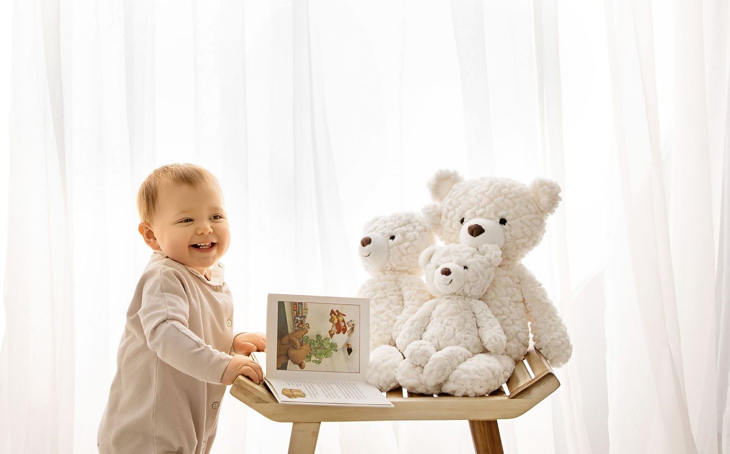 Smiling baby standing by a table during milestone photography session