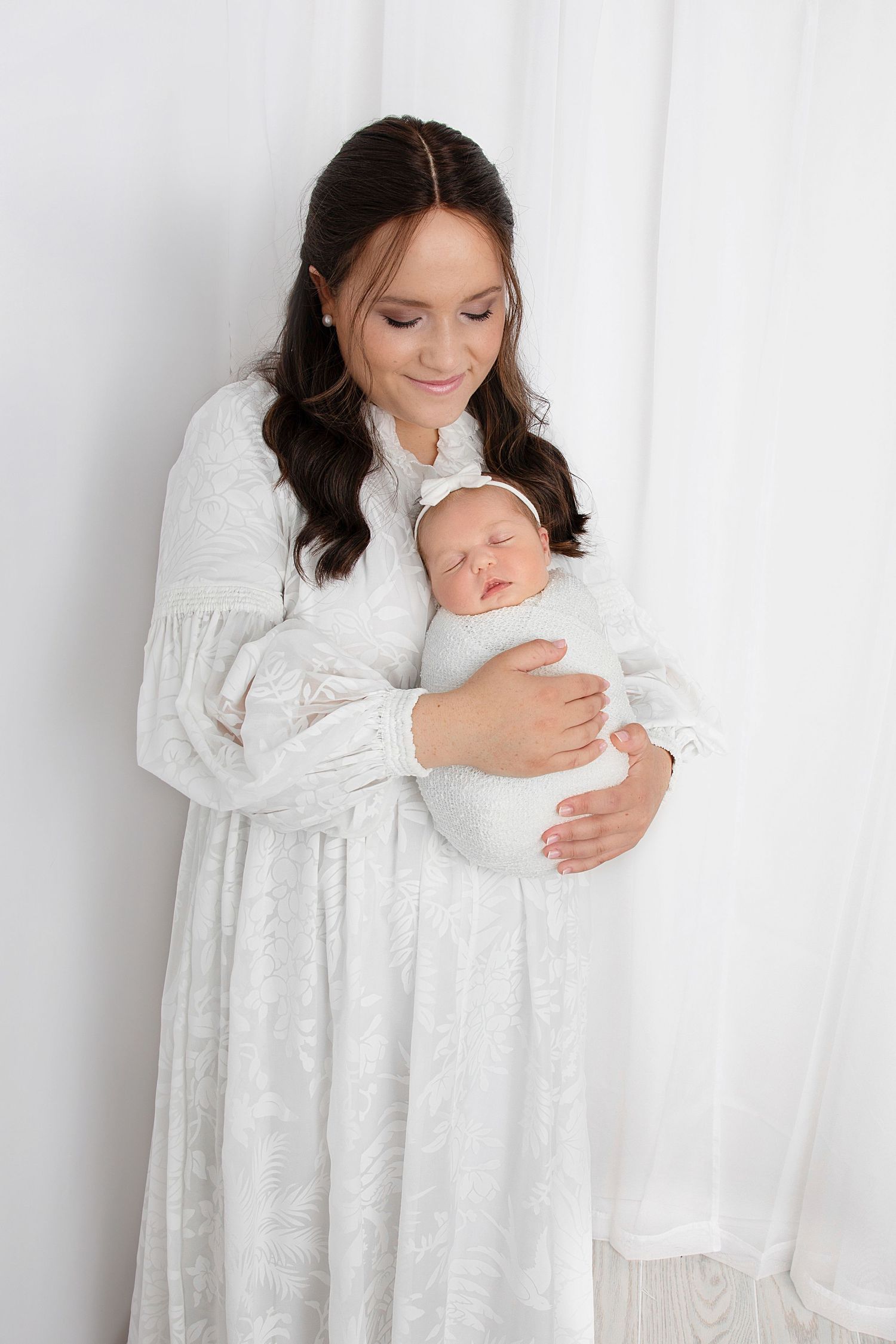 Mother gently holding newborn baby captured by professional family photographers in studio
