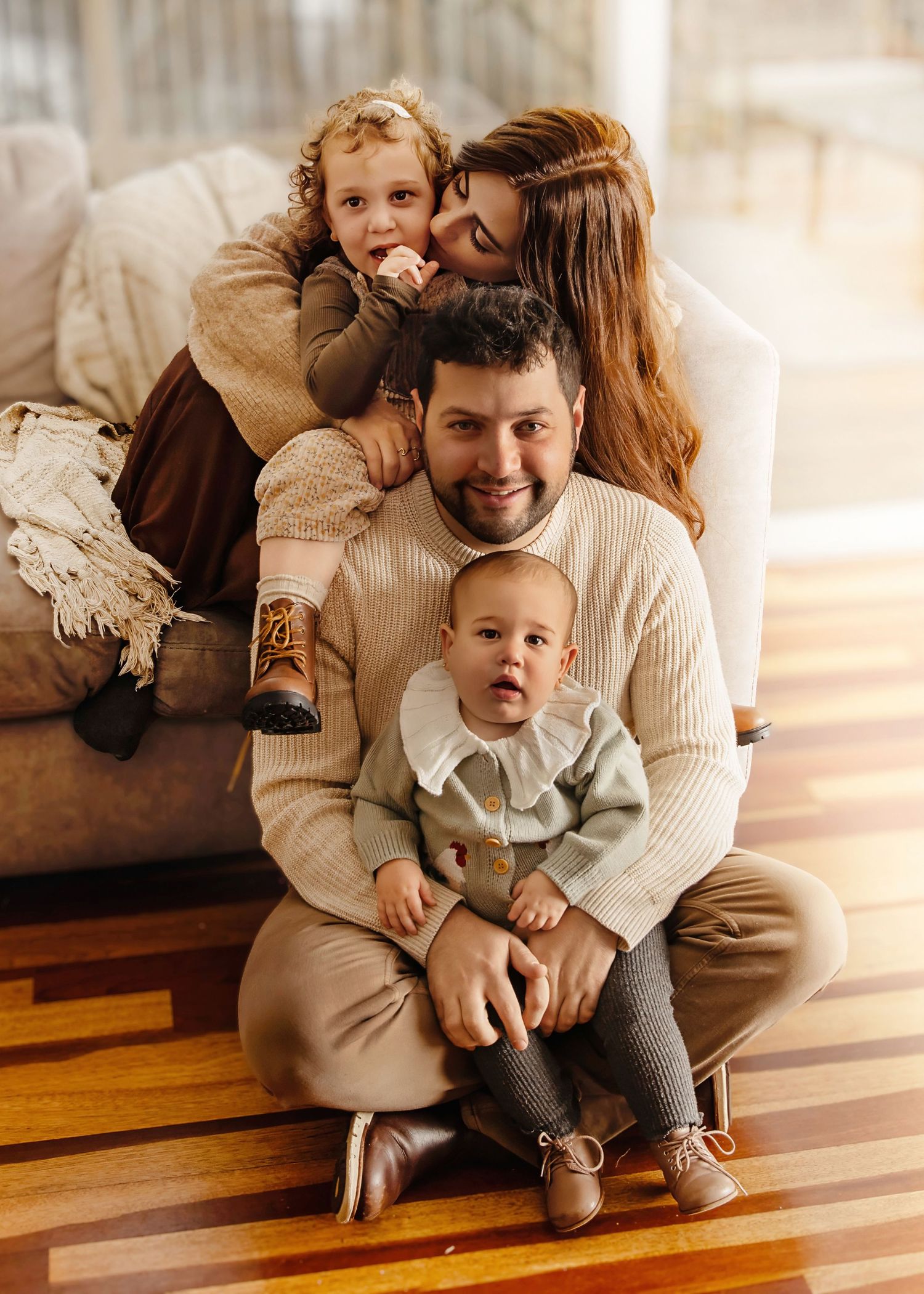 Happy family of four sitting together during indoor family photography session in New Jersey