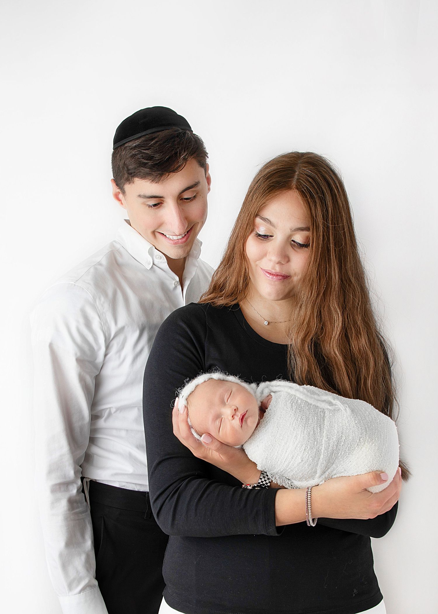 Newborn and family photoshoot with parents holding baby in soft natural portrait setup