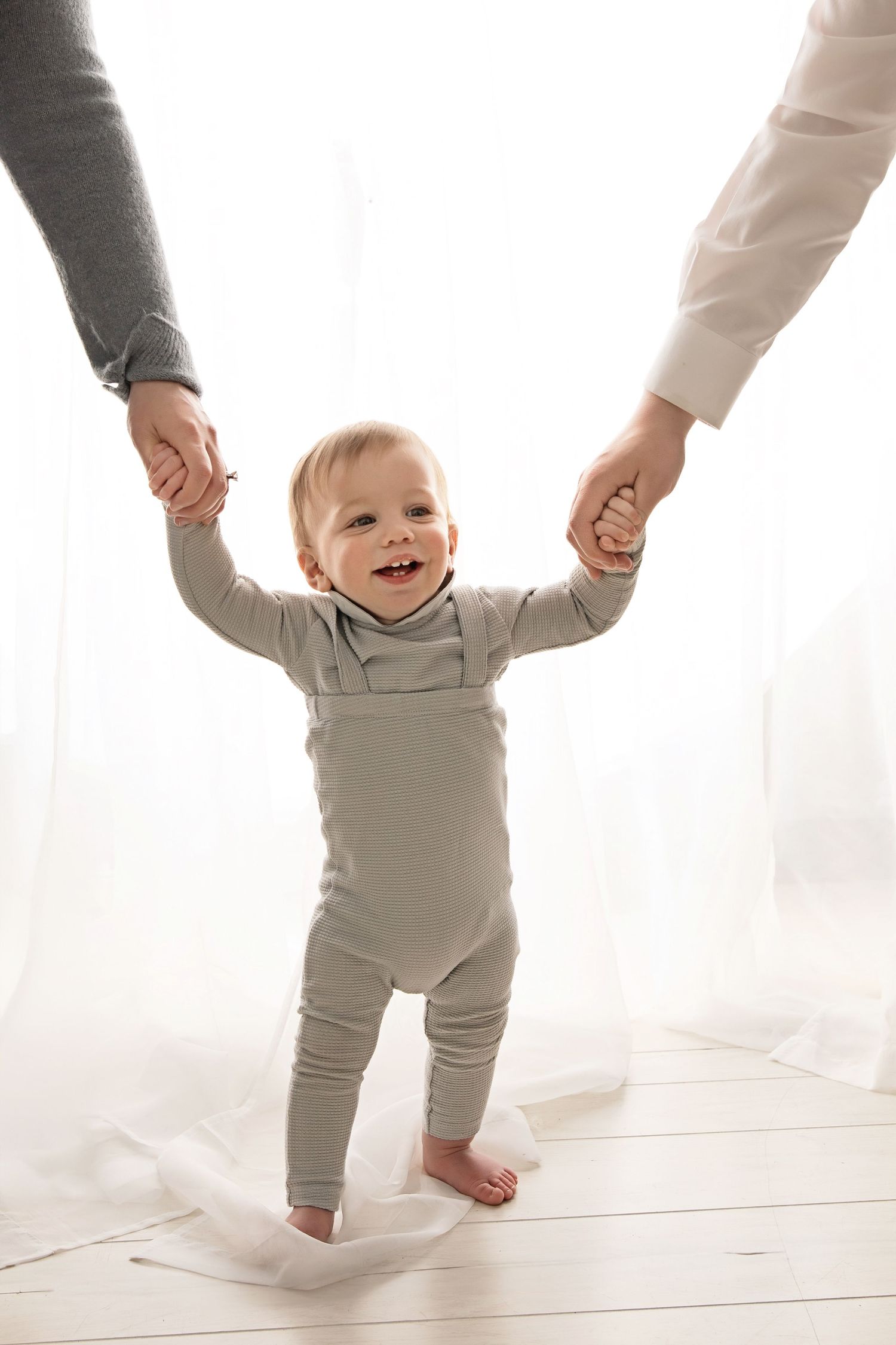 Baby learning to walk while holding parents' hands  milestone photography session in Jackson NJ