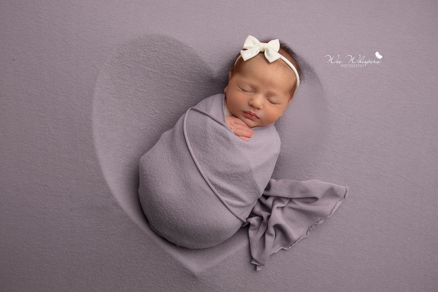 Sleeping baby wrapped in soft blanket during newborn shoot in studio