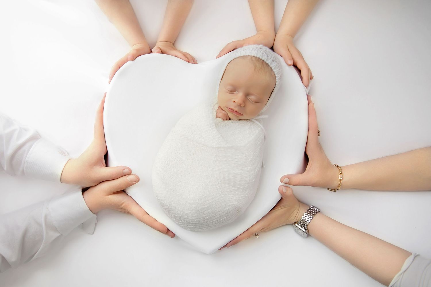 Newborn photos with baby wrapped and placed in heart shaped setup for newborn photography session