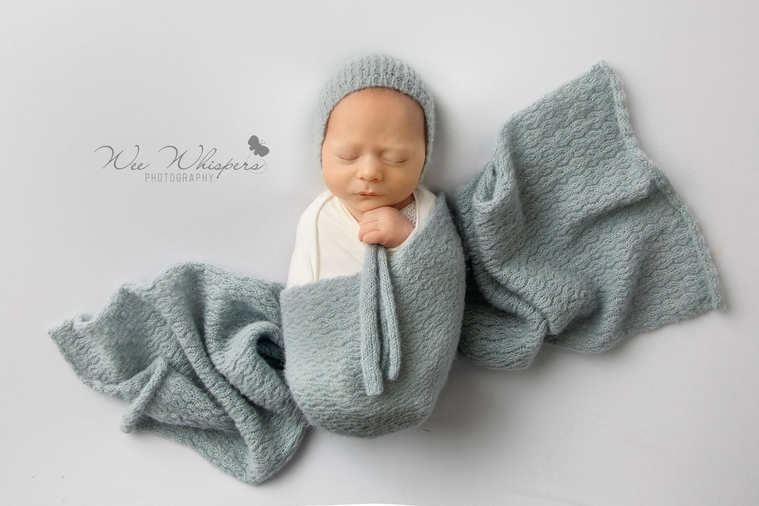 Sleeping baby wrapped in soft textured blanket during cozy newborn photoshoot session