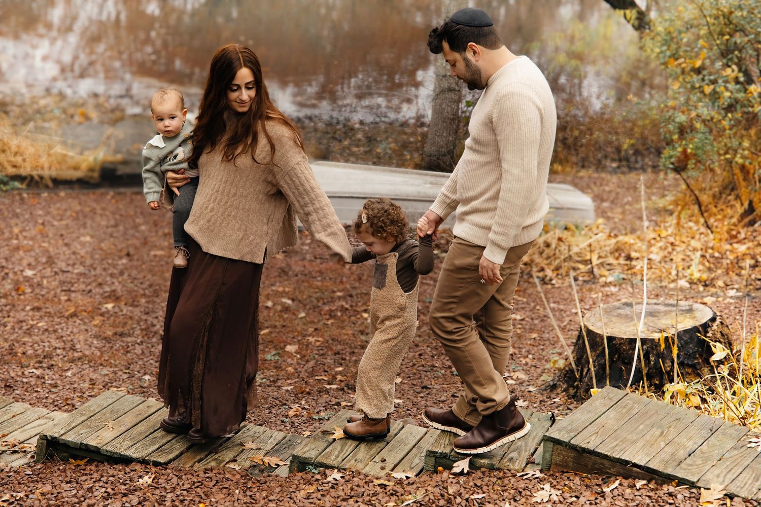 Family with toddler sitting by a lake during outdoor family portraits in Central NJ