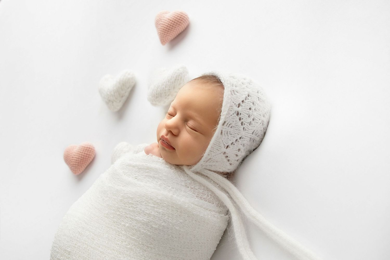 Peacefully sleeping newborn in knit bonnet with soft neutral styling in Toms River NJ studio