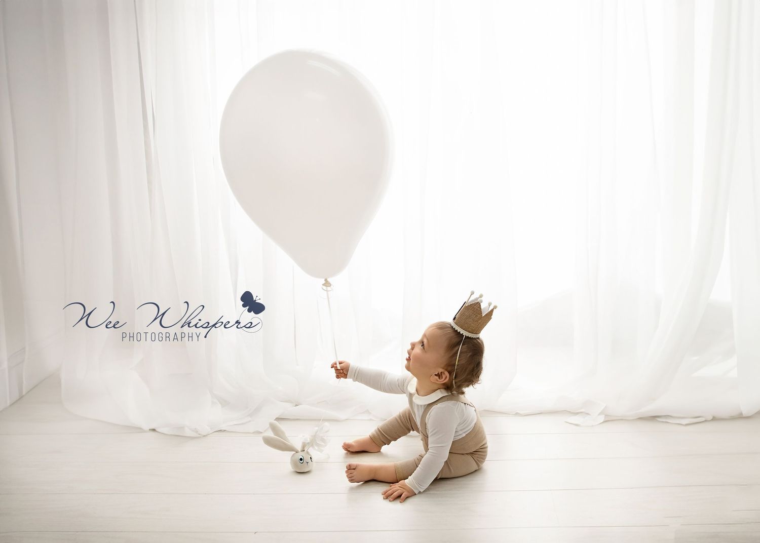Baby crawling and playing in bright white studio with natural window light.