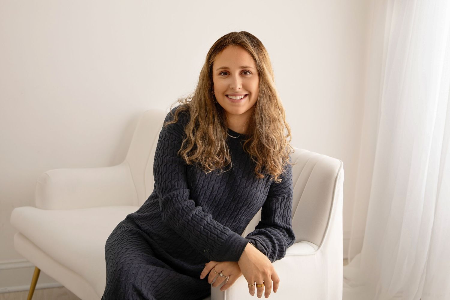 Lifestyle portraits of someone in casual attire seated on white furniture.