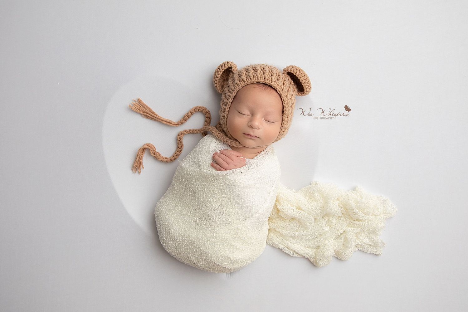Sleeping baby wrapped in soft blanket with knit hat during newborn photos session