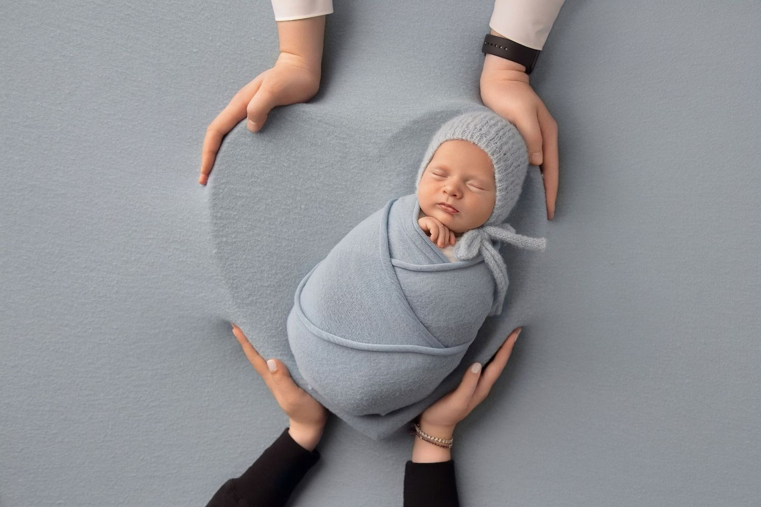 Newborn photography with baby wrapped in blanket, professional infant photography setup