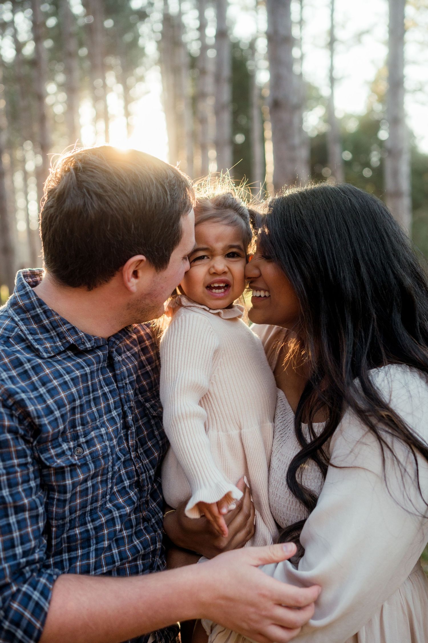 Family sharing a joyful moment together in a sunlit forest setting.