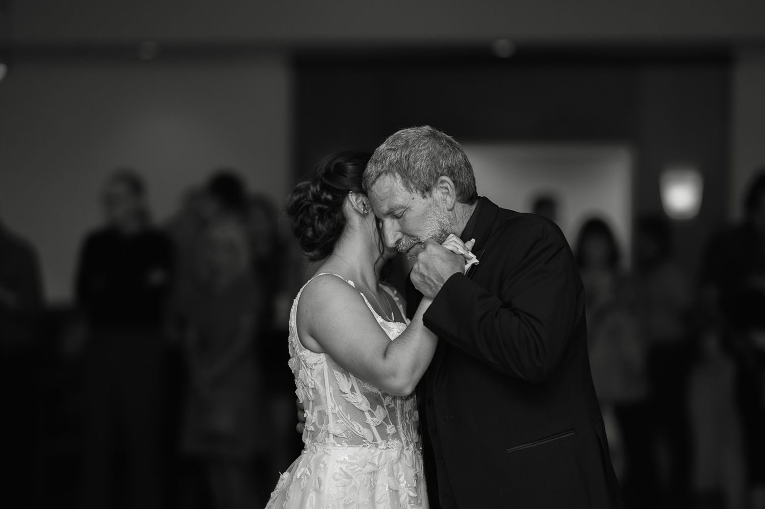 Black and white photo of bride and groom sharing first dance kiss at wedding reception.