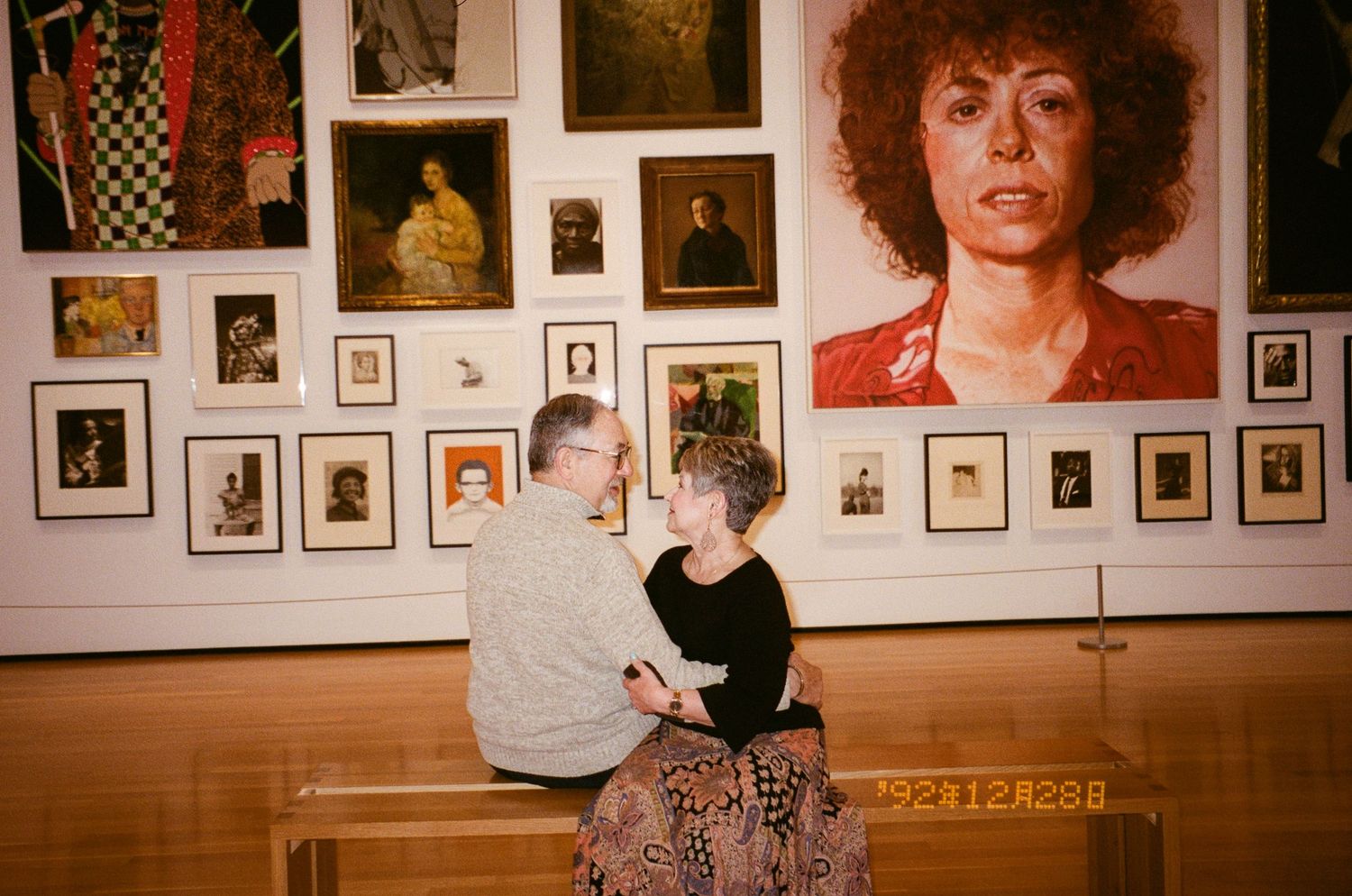 A wall gallery displays numerous framed photographs and portraits in warm lighting against a white background.