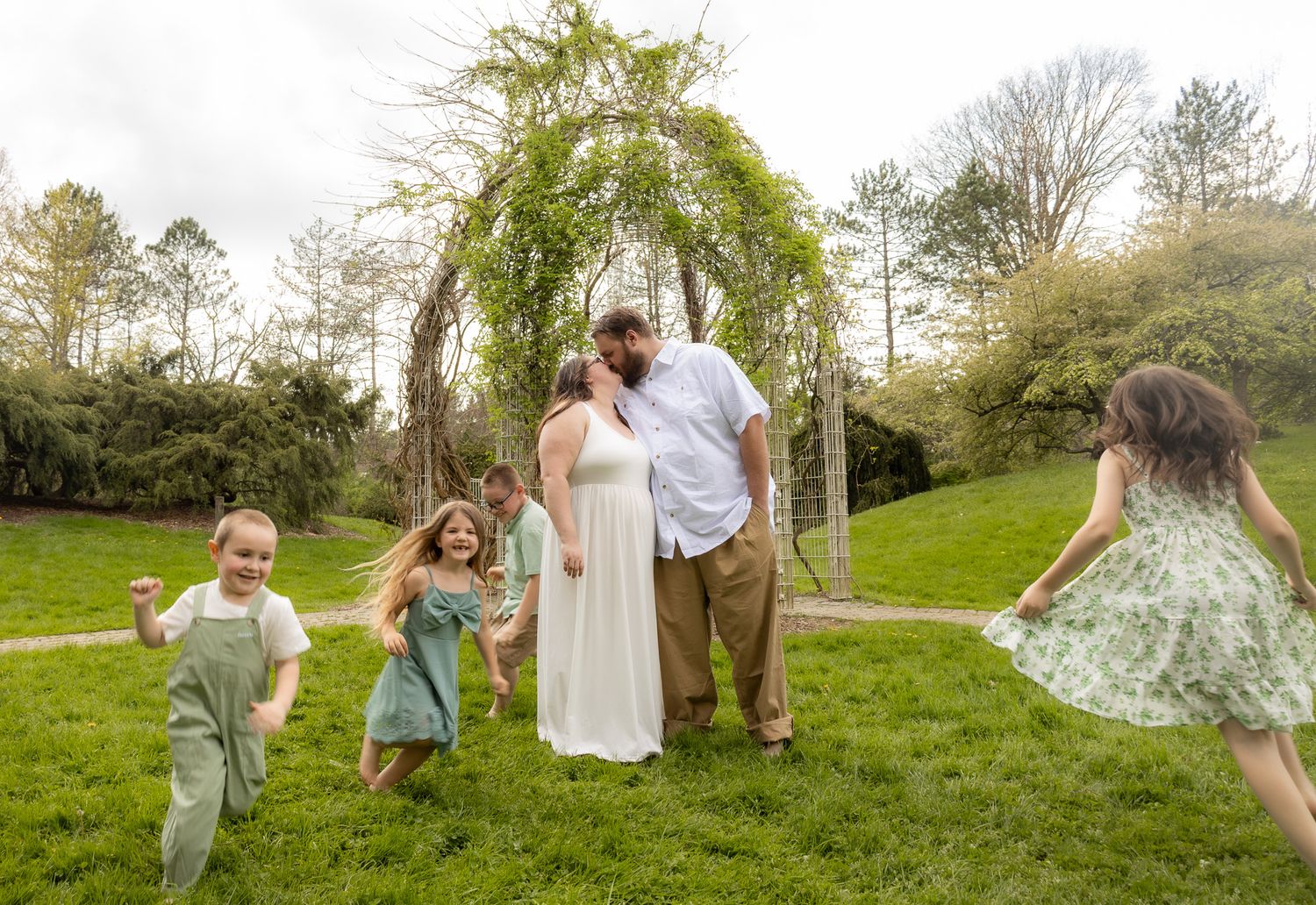 Playful family moments captured in series of outdoor photos on grassy hillside.