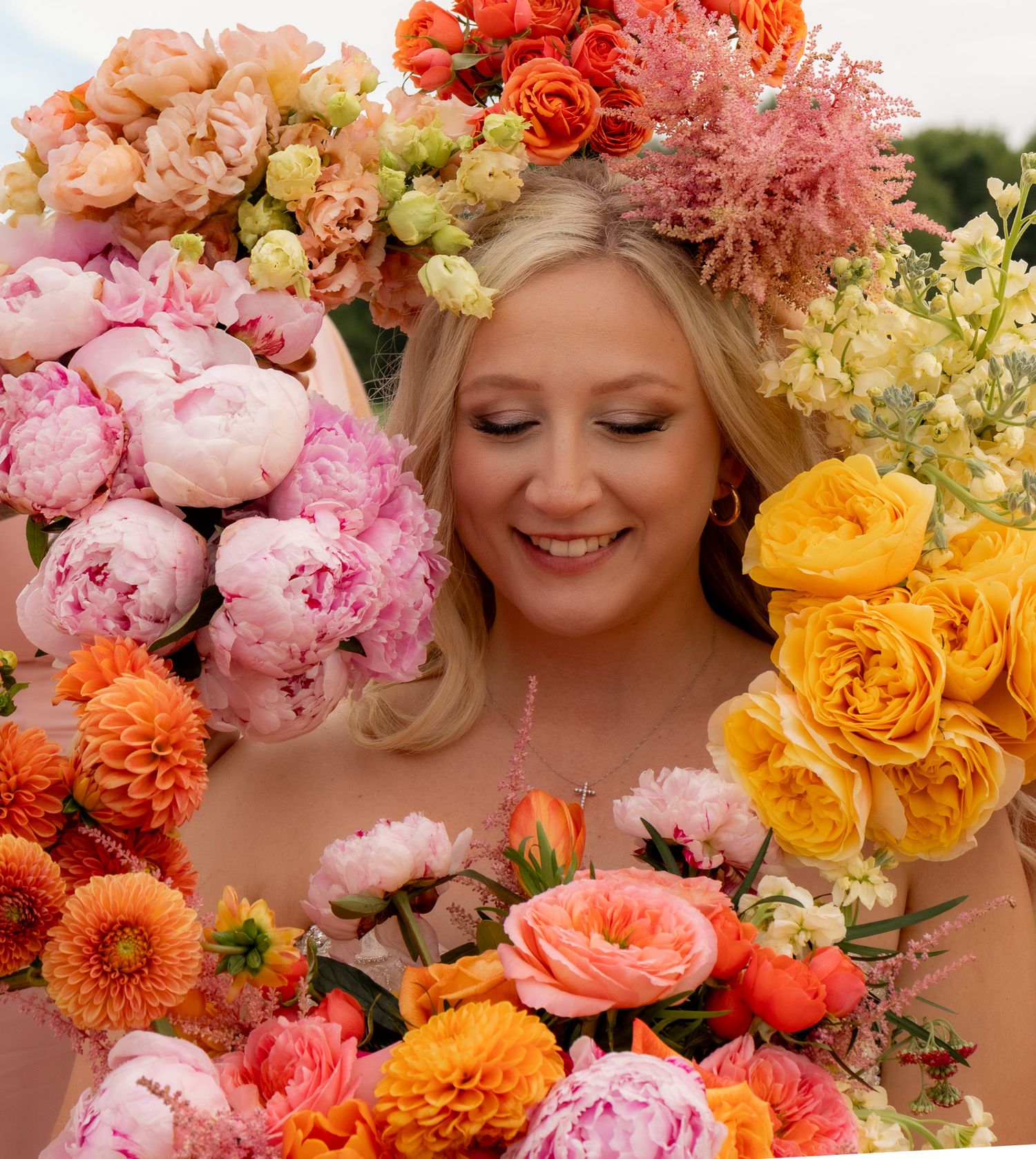 Beautiful floral crown featuring pink peonies, orange roses, and yellow blooms in a romantic arrangement.