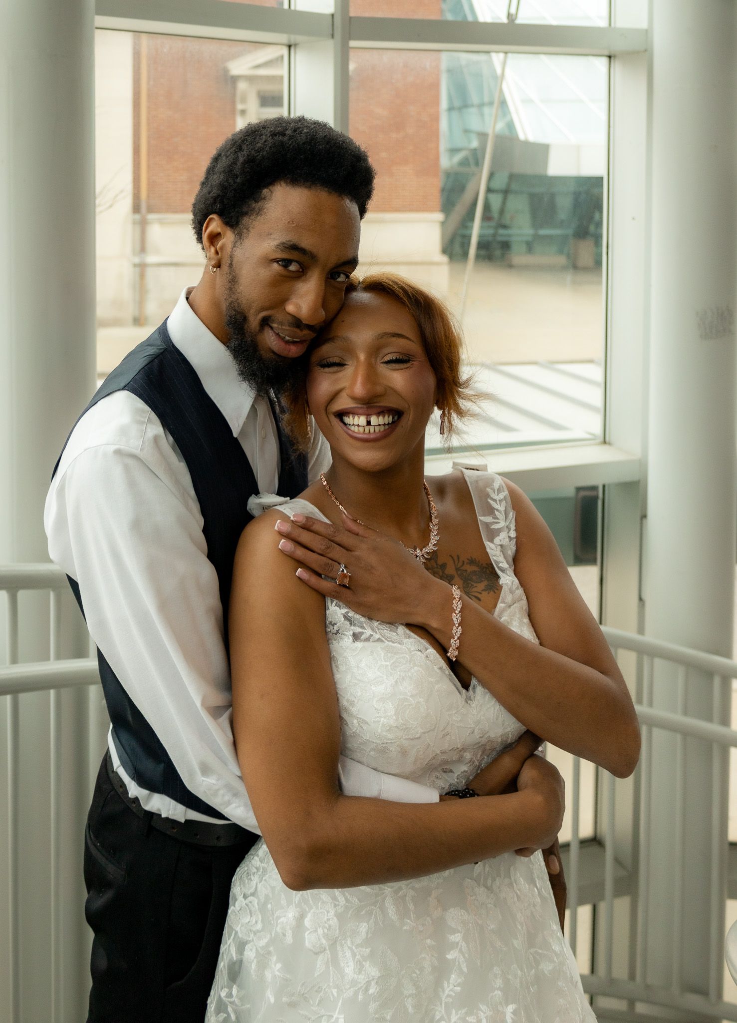 Wedding couple sharing intimate moments in bright indoor space with white columns.