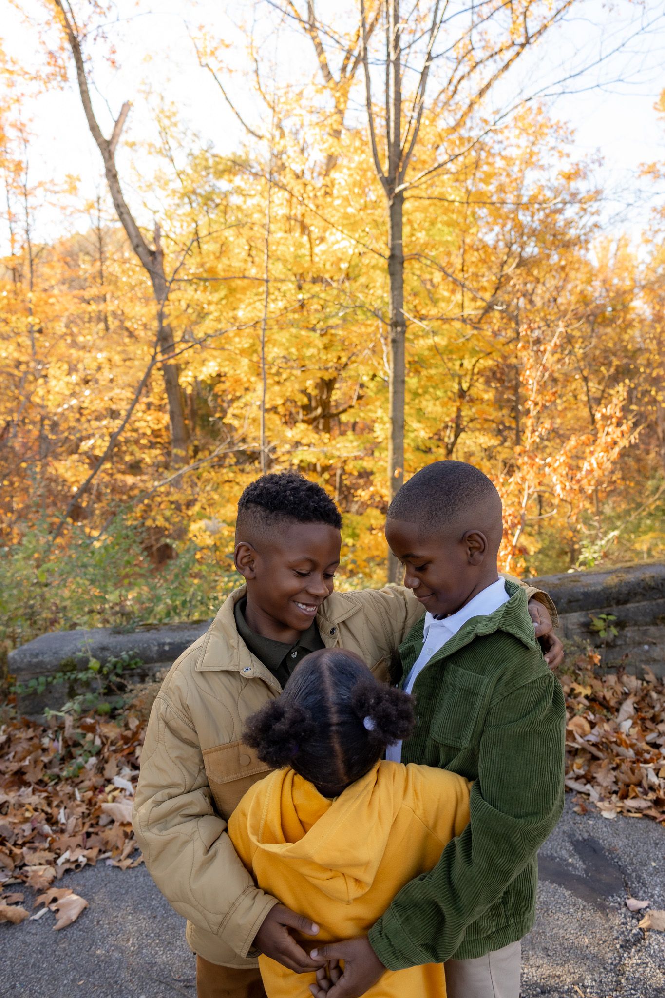 Autumn photoshoot in a park with golden leaves and warm lighting.
