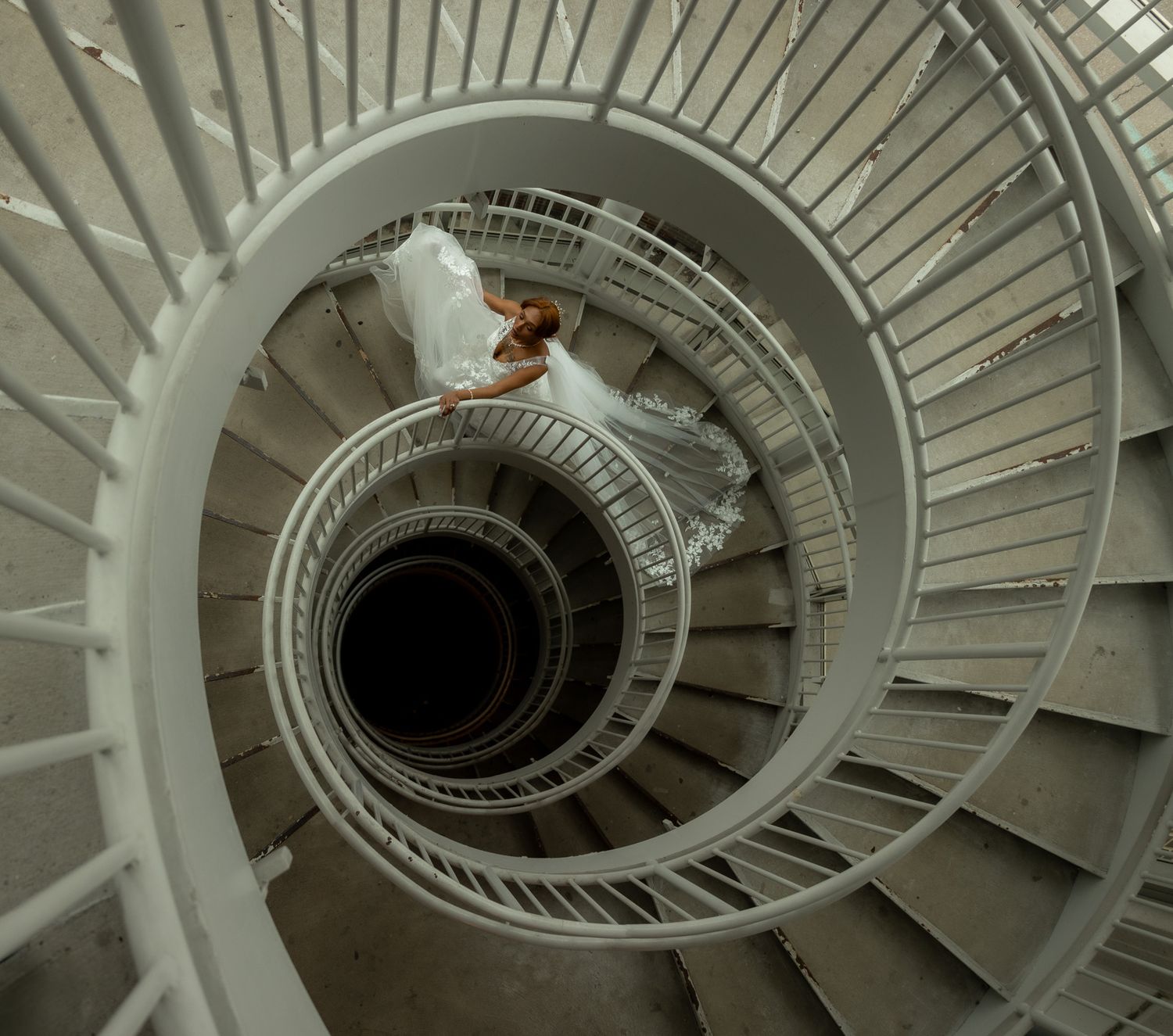Spiral staircase photographed from above showing geometric white circular pattern.