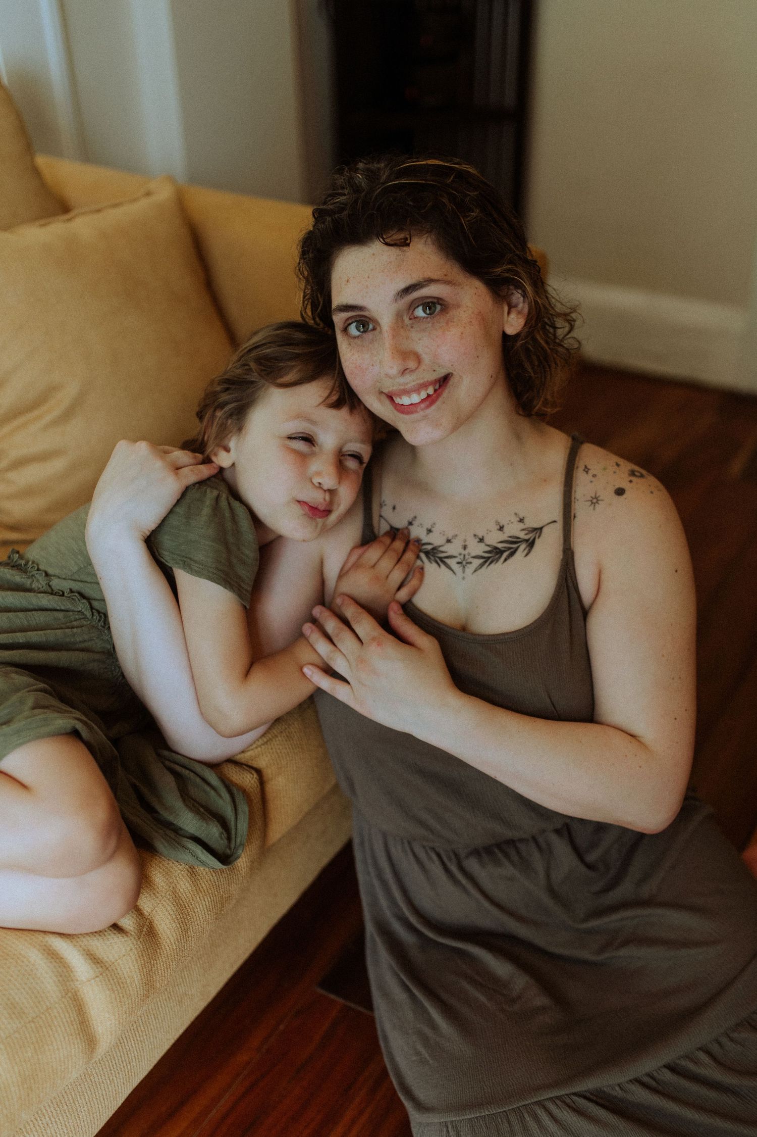 Intimate lifestyle portraits of parent and child relaxing together on yellow couch.