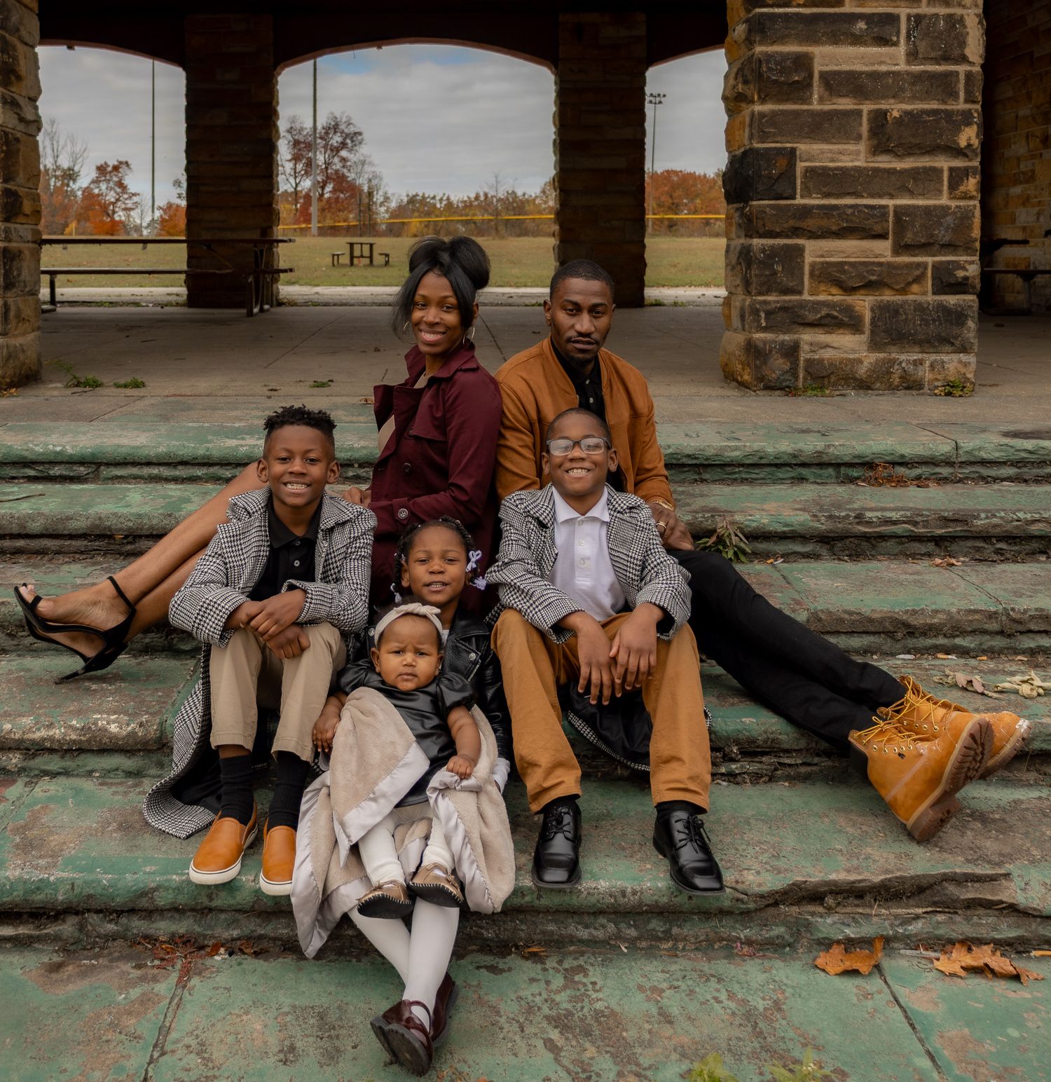 Family sitting together on stone steps during an autumn outdoor photo session.