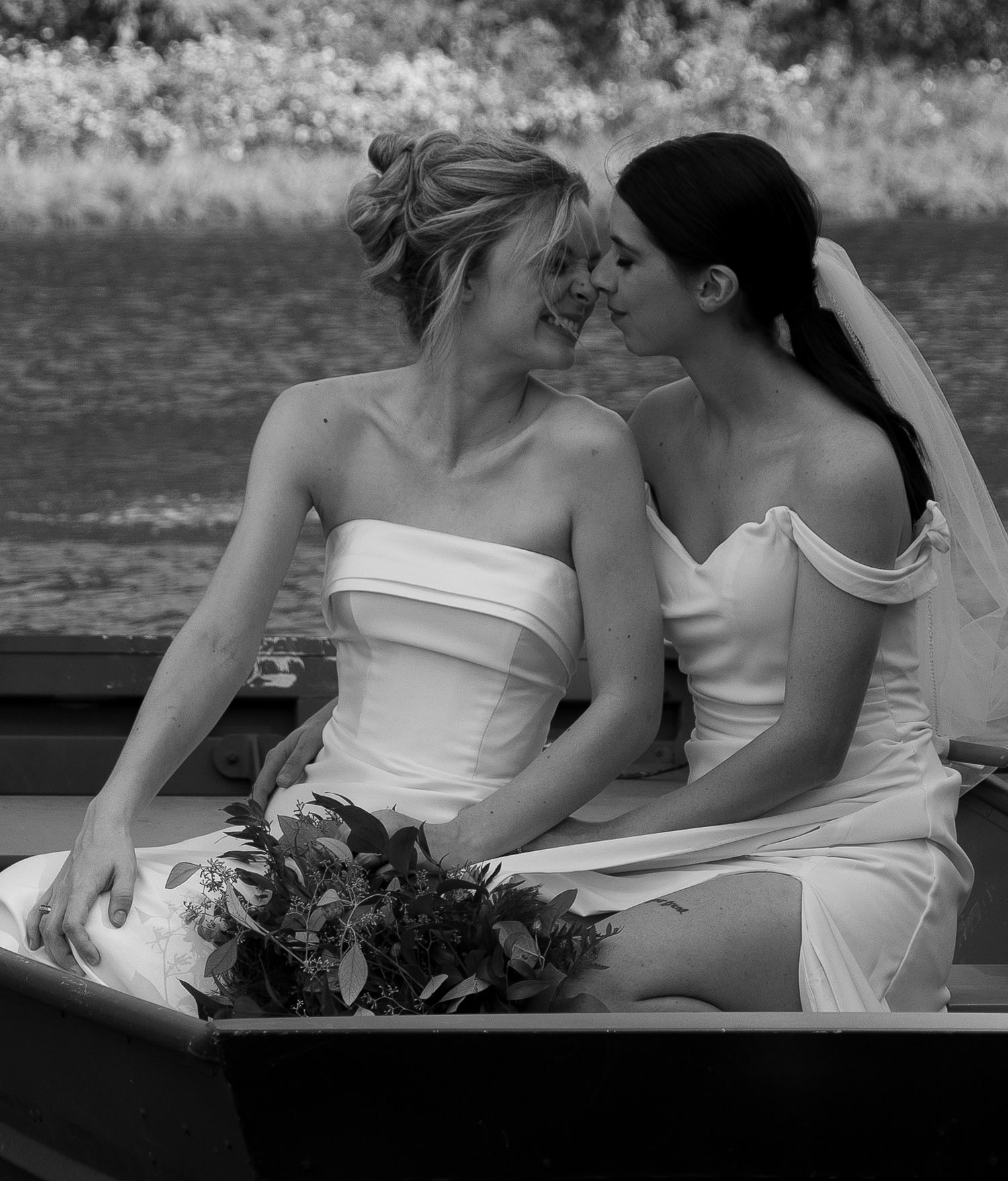 Black and white photo of two people in white dresses sitting close together.
