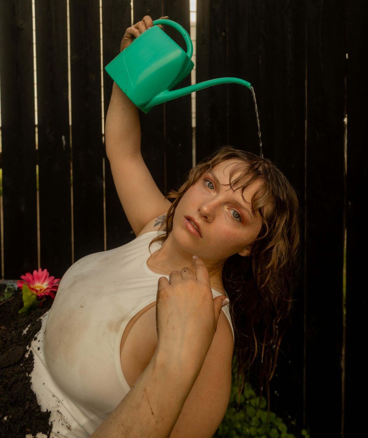 A creative photo series of someone pouring water from a green watering can in a backyard garden setting.