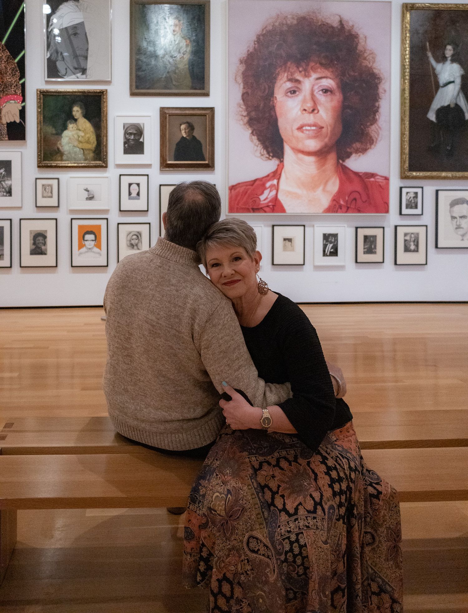 A series of gallery photos showing two people in casual attire looking at artwork displayed on a wall.