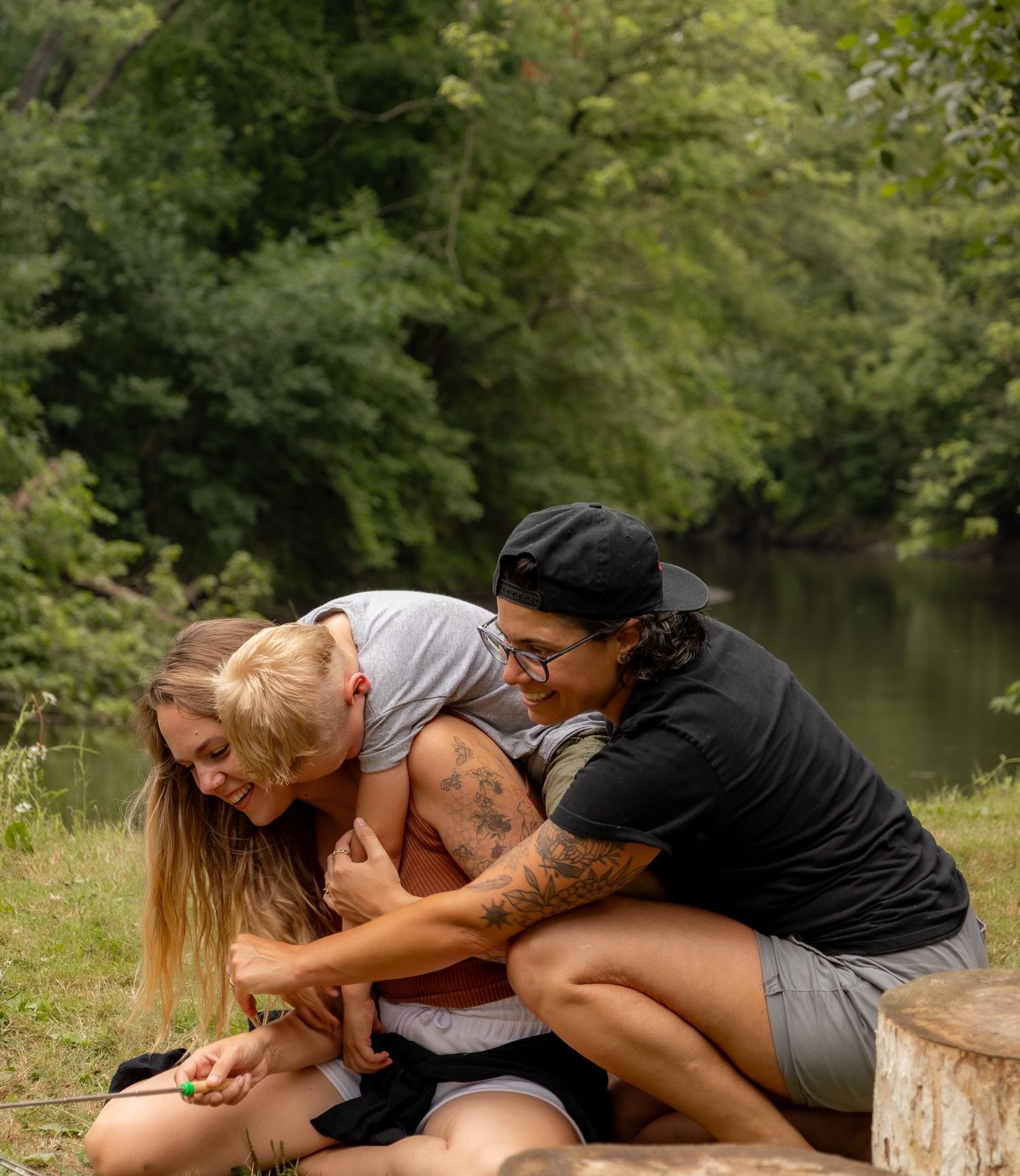 A group of people perform a playful domino-style falling sequence on a wooden dock by a peaceful lake.