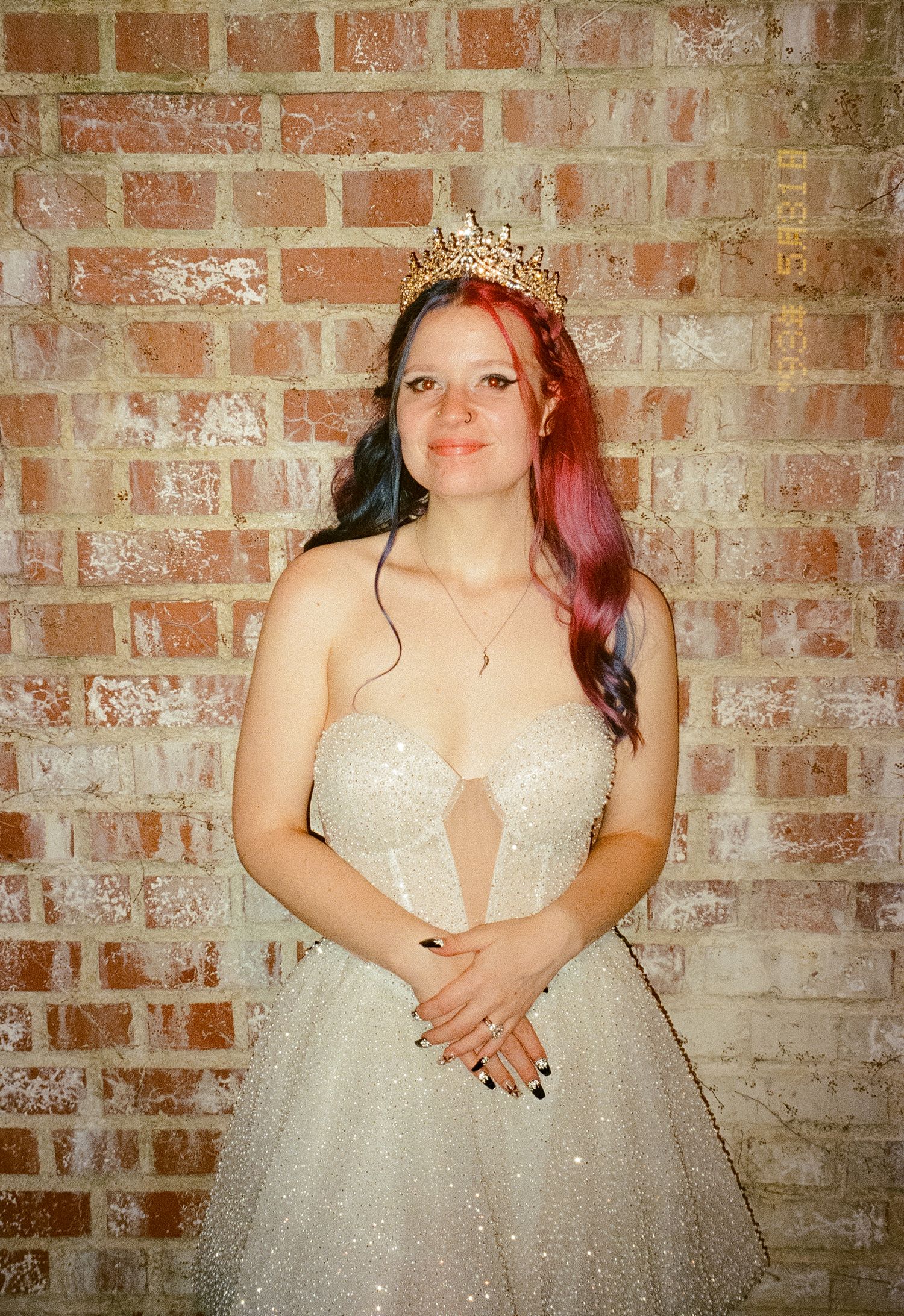 A bride in a sparkly white ballgown poses against a rustic brick wall in a series of candid shots.