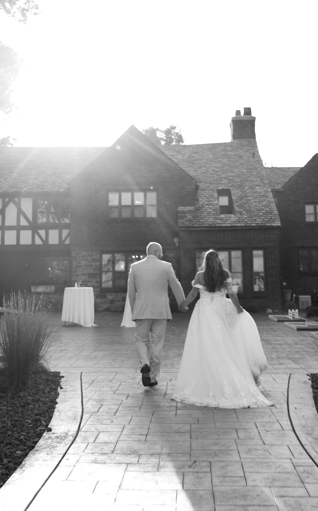 Black and white wedding sequence shows couple walking away on stone patio in multiple progressive frames.