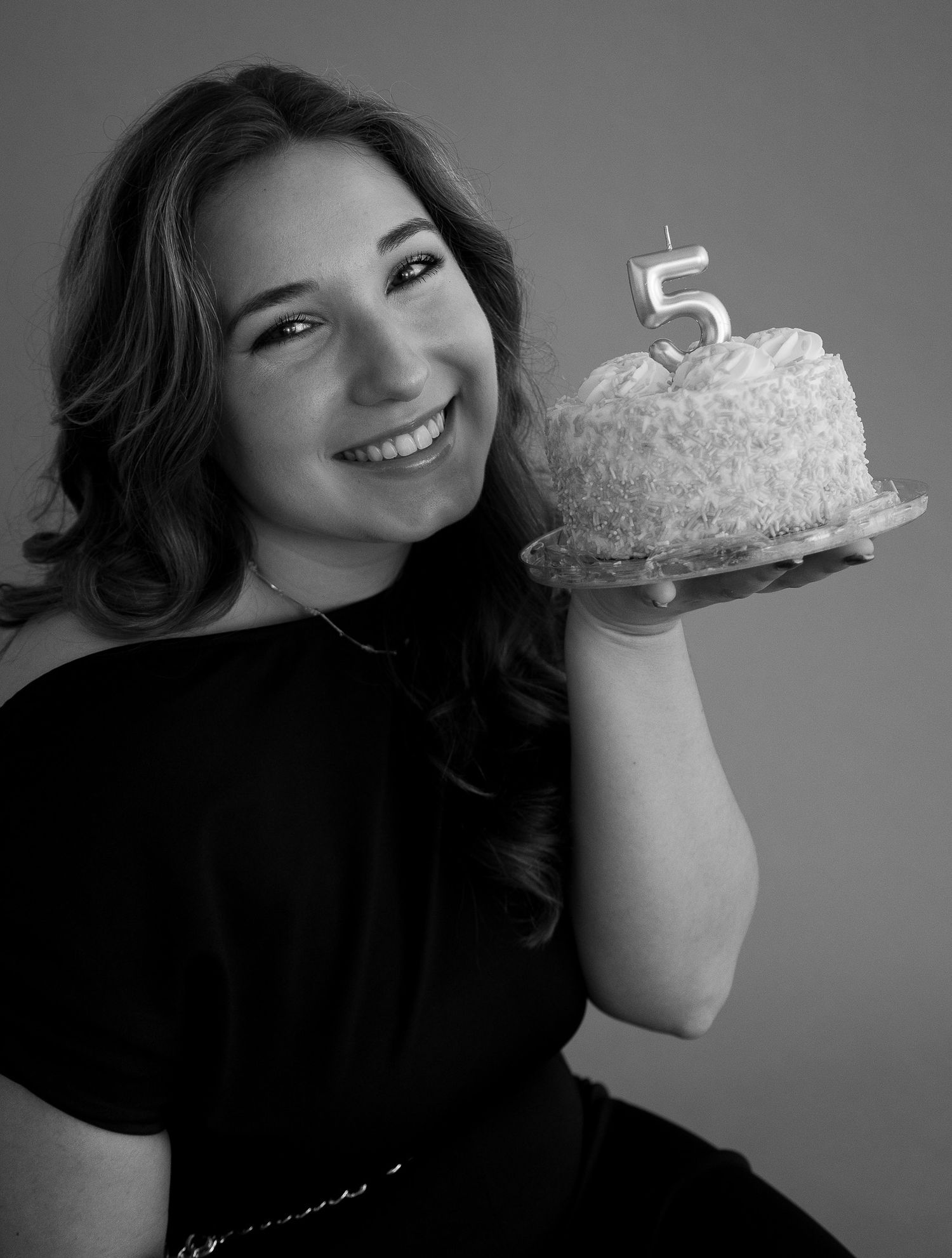 Black and white photo series showing someone joyfully posing with a birthday cake in different playful expressions.
