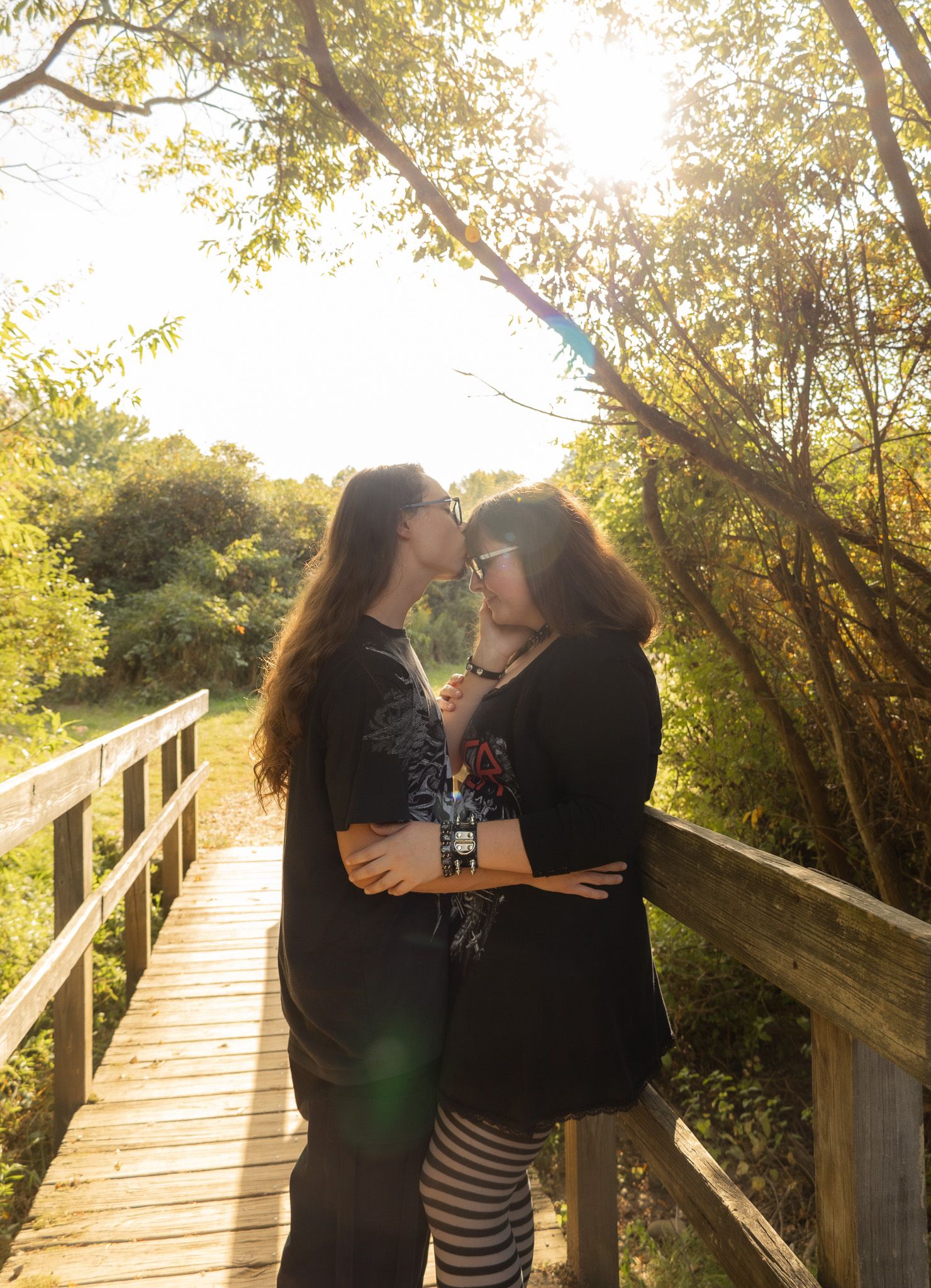 Couple sharing intimate moments on wooden walkway during sunset.