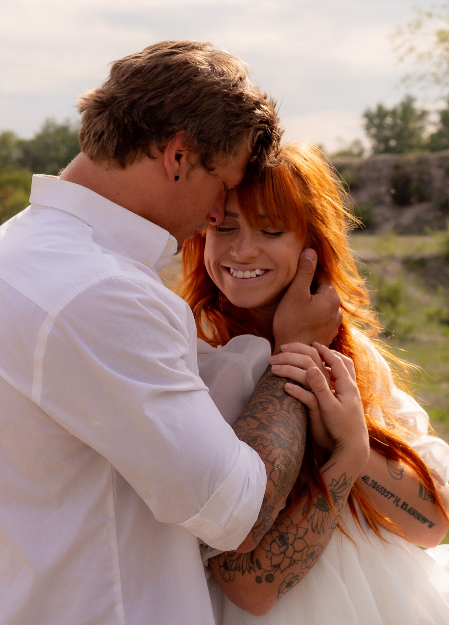 Romantic couple embraces at sunset with warm golden light illuminating their intimate moment.
