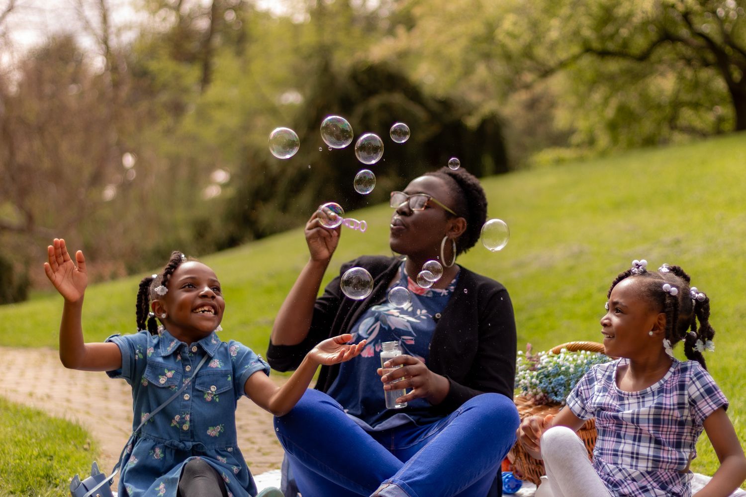 A group of people laugh and enjoy themselves while sitting outdoors on a sunny day in a park setting.