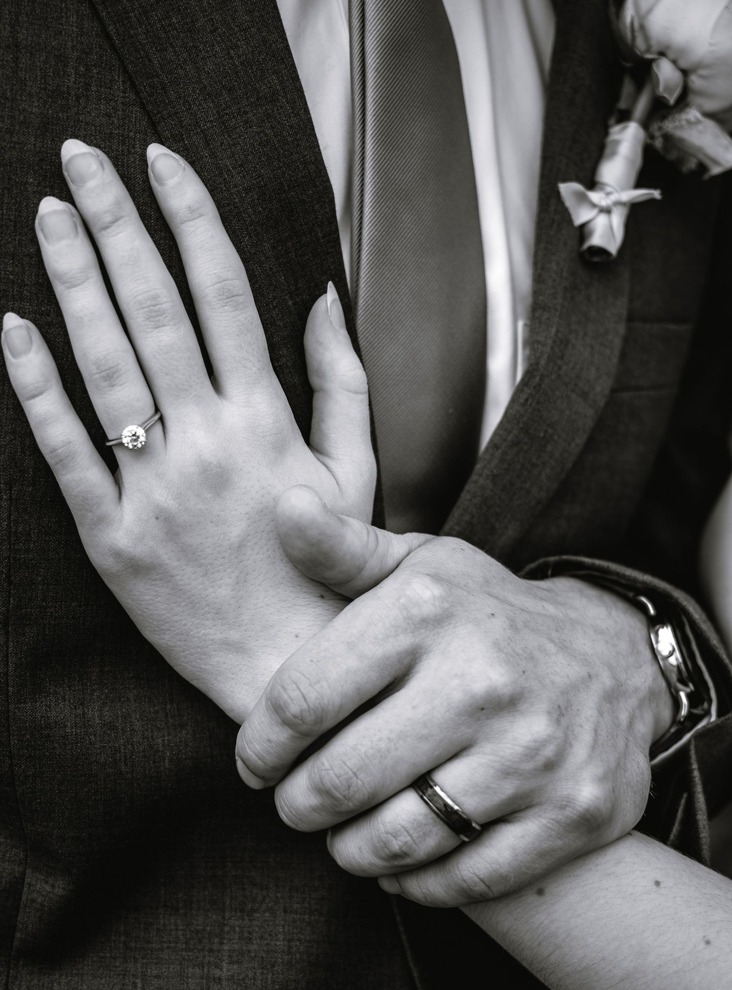 Black and white photo of newlyweds hands showing diamond engagement ring and wedding band.