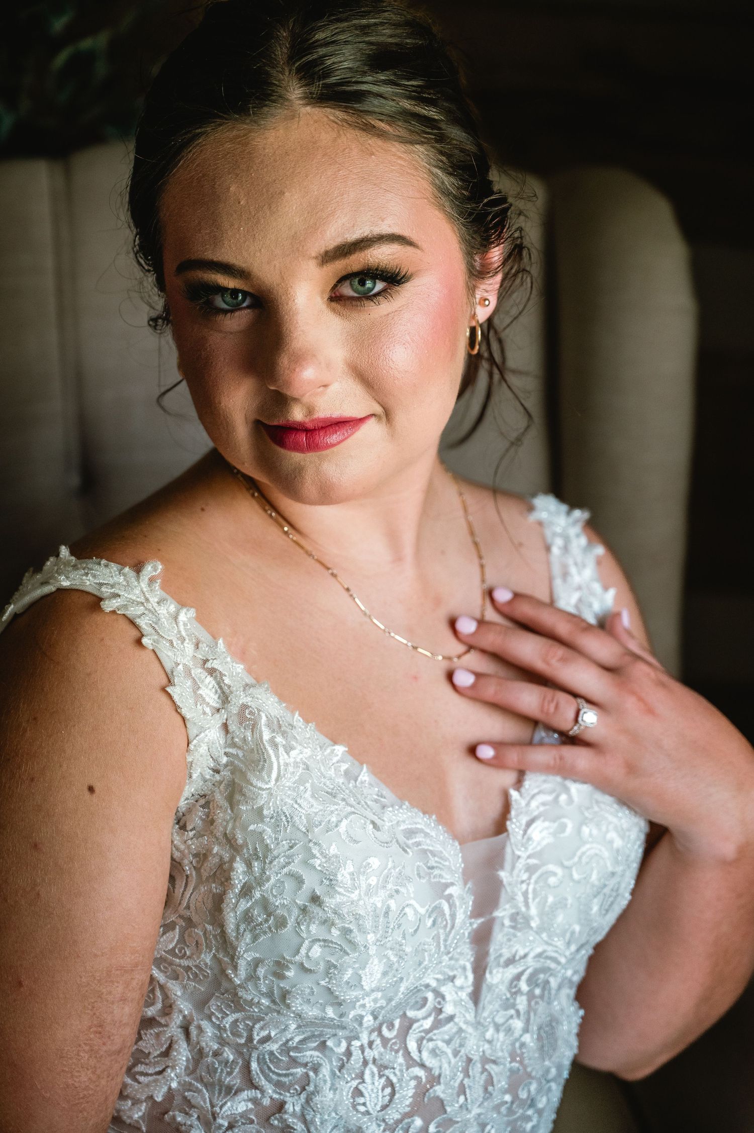 Close up portrait of a bride wearing a white lace wedding dress with plunging neckline and delicate necklace.