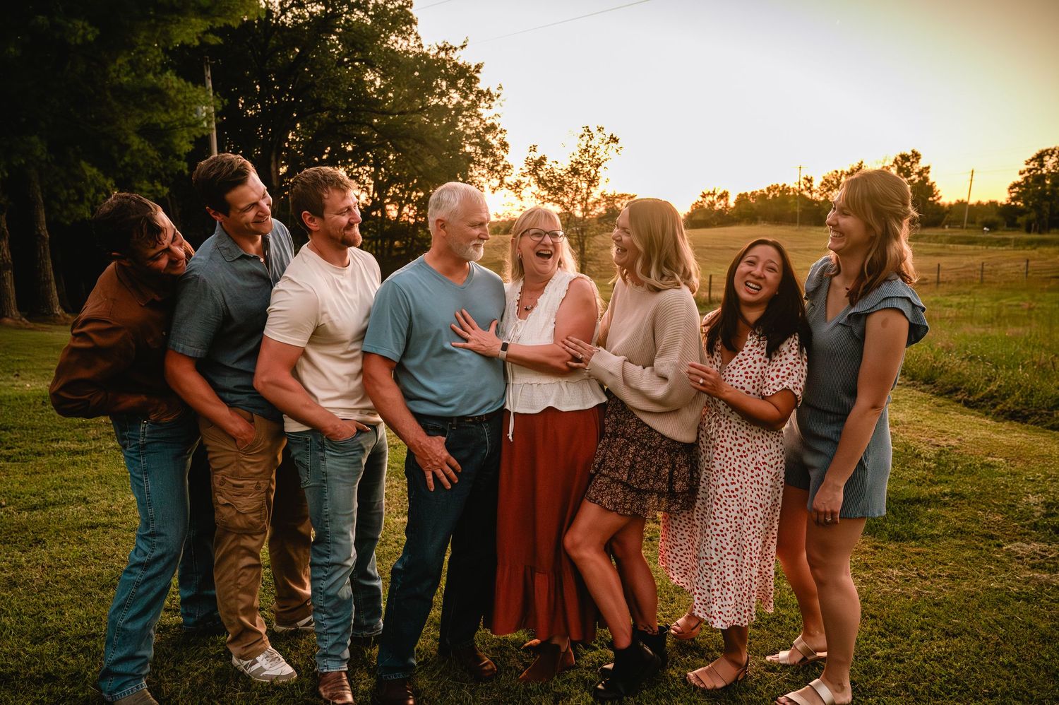 A group of people standing together in a field at sunset, creating a warm and intimate gathering atmosphere.