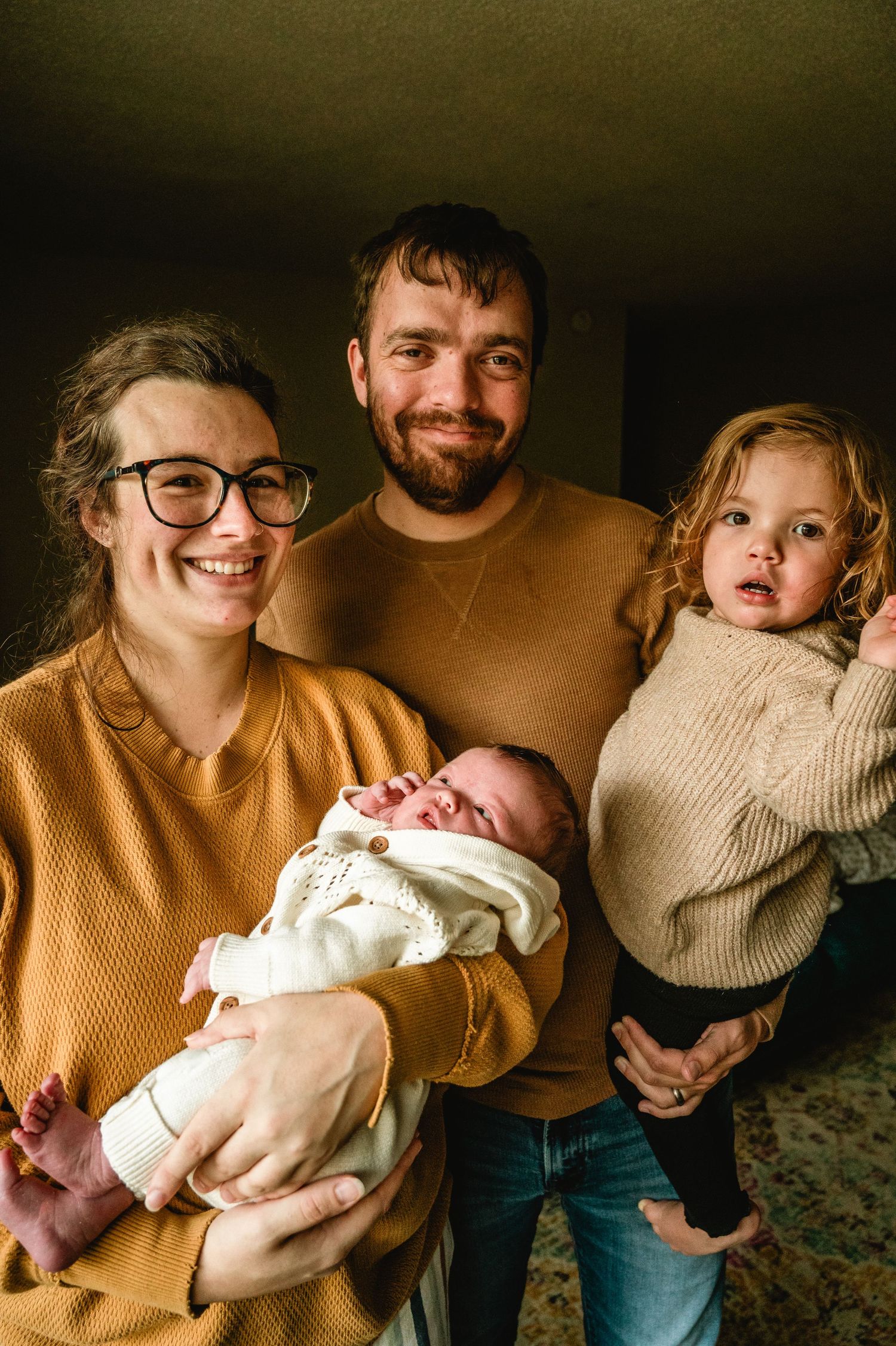 A series of warm-toned photos showing a couple holding and bonding with their newborn baby in casual home setting.