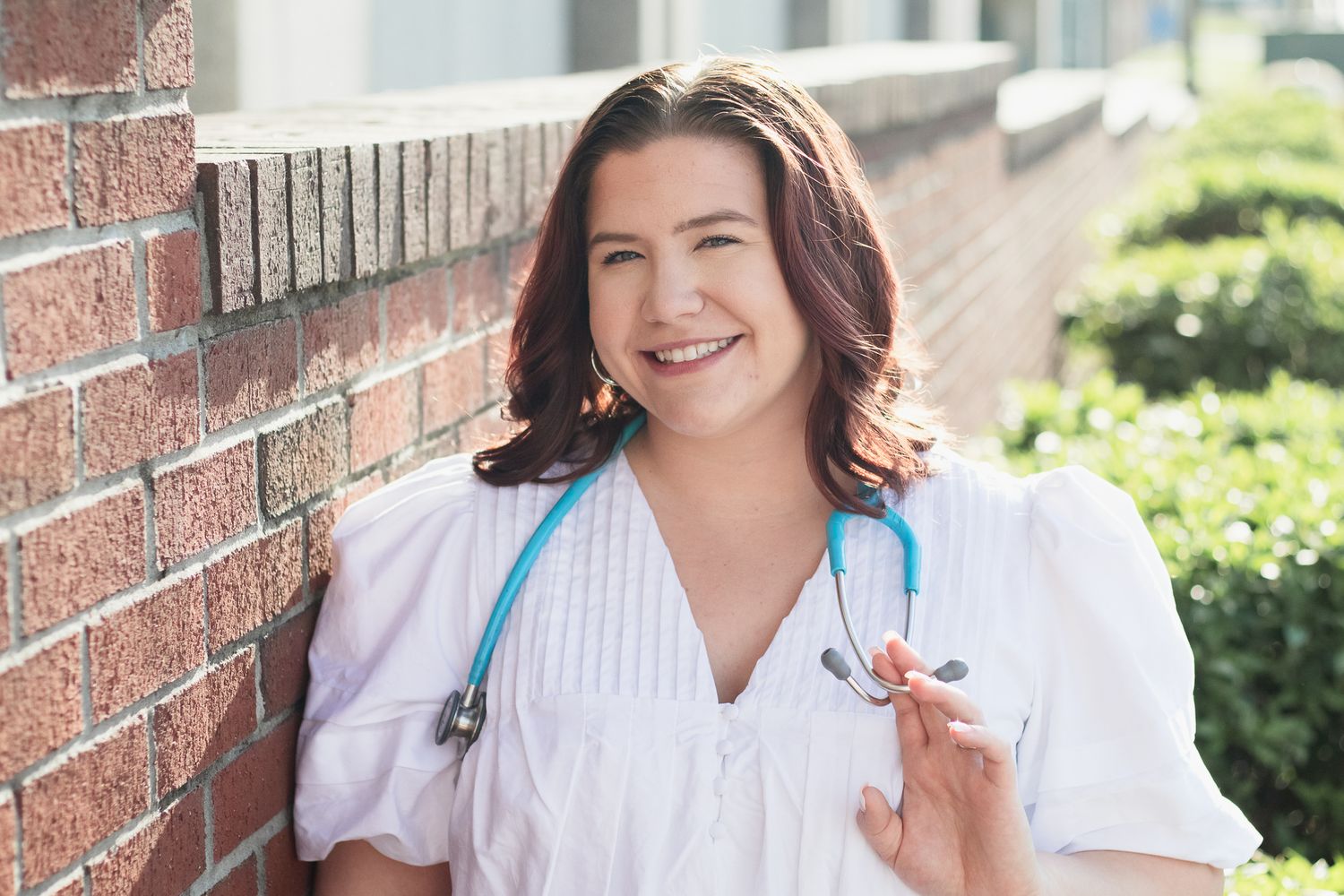 Nursing college graduate portraits posing for a South Carolina photographer in Florence, SC for their senior pictures. stethoscope textbooks